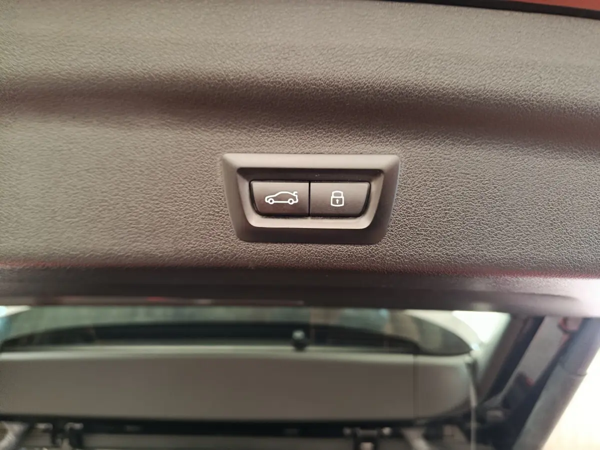 Boutons de fermeture et verrouillage électrique du coffre vus de l'intérieur du hayon d'un BMW X1 noir 2023.
