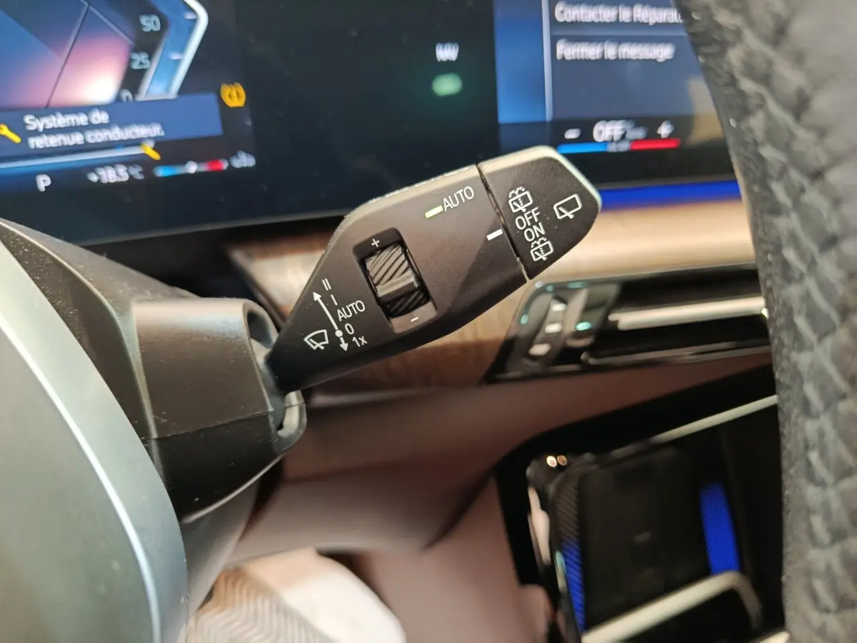 Gros plan sur la commande d’essuie-glace à gauche du volant dans l’habitacle d’une BMW X1 noire 2023.