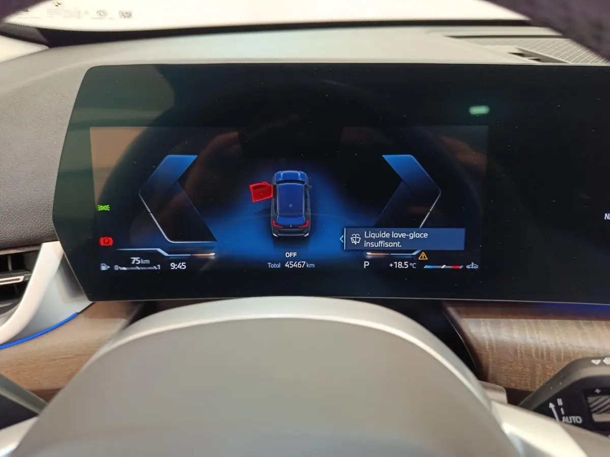 Vue rapprochée du combiné d'instruments numérique du BMW X1 2023, affichant une alerte liquide lave-glace insuffisant.