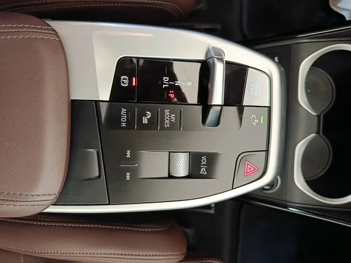 Vue rapprochée de la console centrale du BMW X1 2023, avec levier de boîte auto et accoudoir cuir marron.