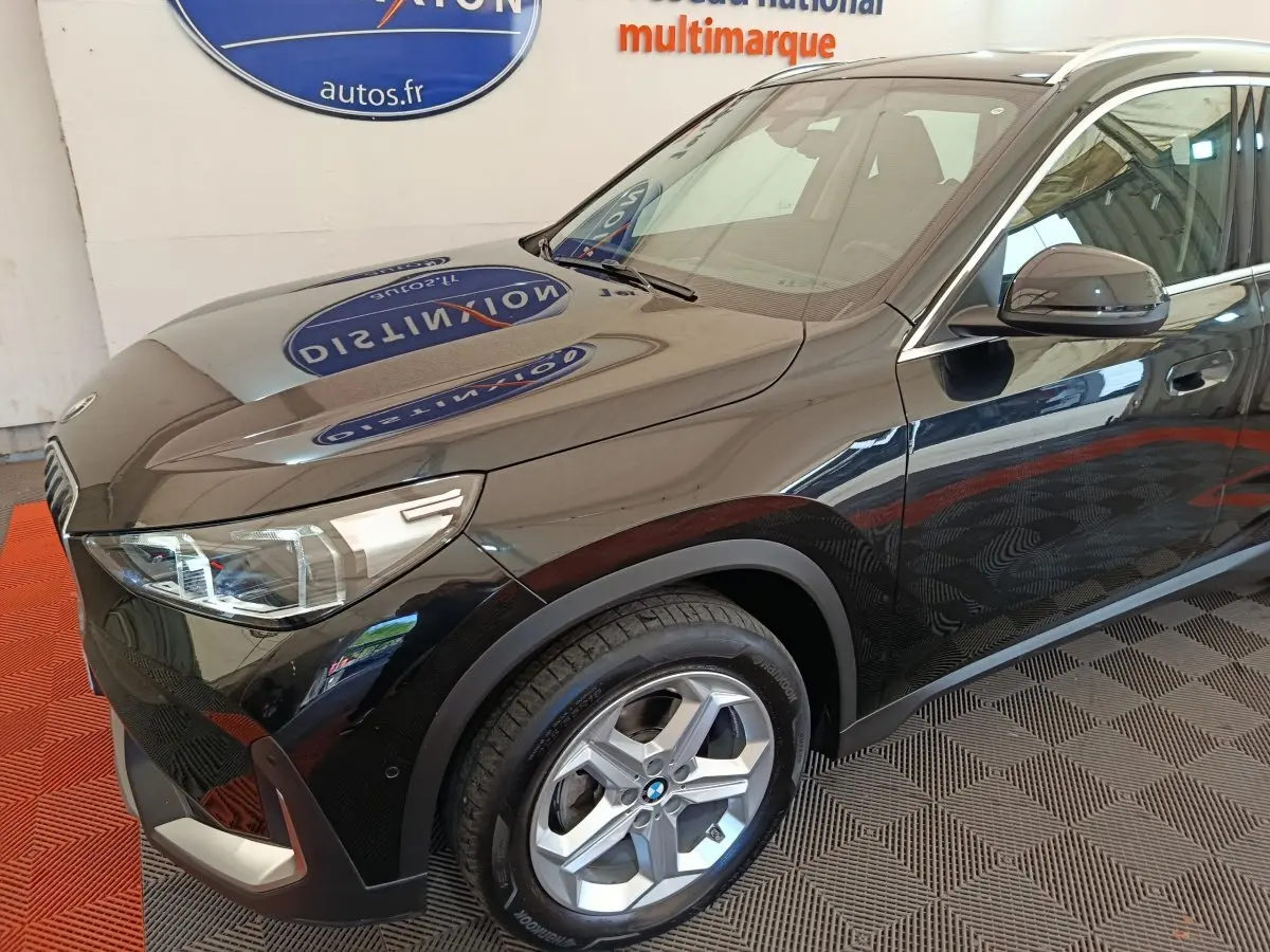 BMW X1 sDrive18i noir vue 3/4 avant droit, mettant en valeur les phares LED et la jante alliage.