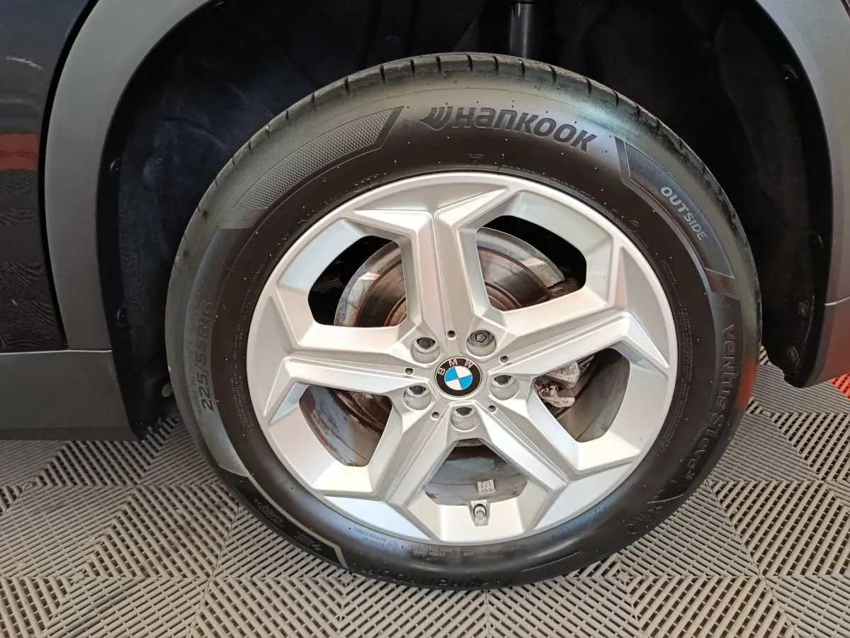Gros plan sur la roue avant droite avec jante argentée et pneu Hankook du BMW X1 noir 2023.