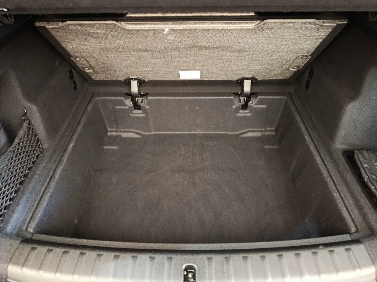 Coffre ouvert vu de dessus d’un BMW X1 noir 2023, espace de rangement profond avec revêtement textile gris foncé.