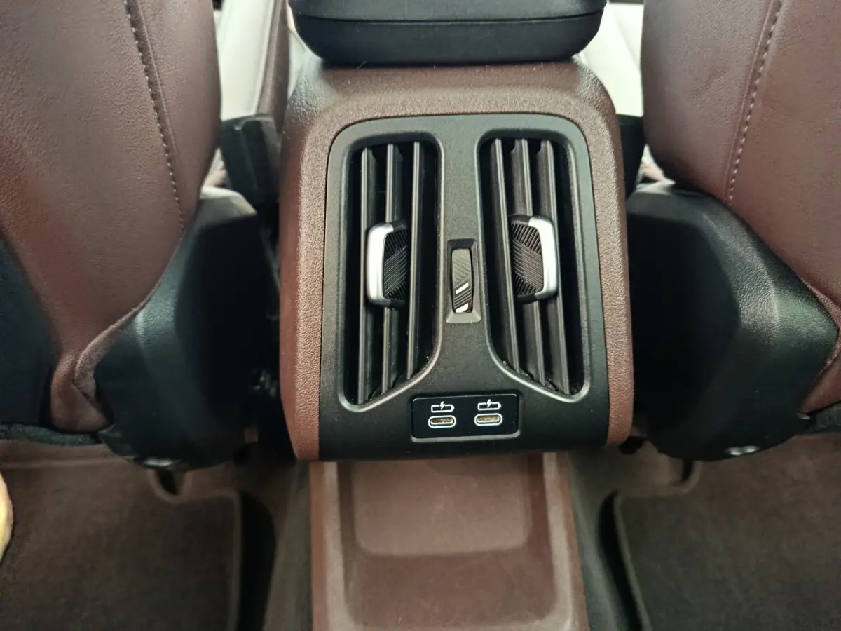 Vue rapprochée des aérateurs arrière et ports USB-C noirs au centre entre les sièges marron du BMW X1 2023.