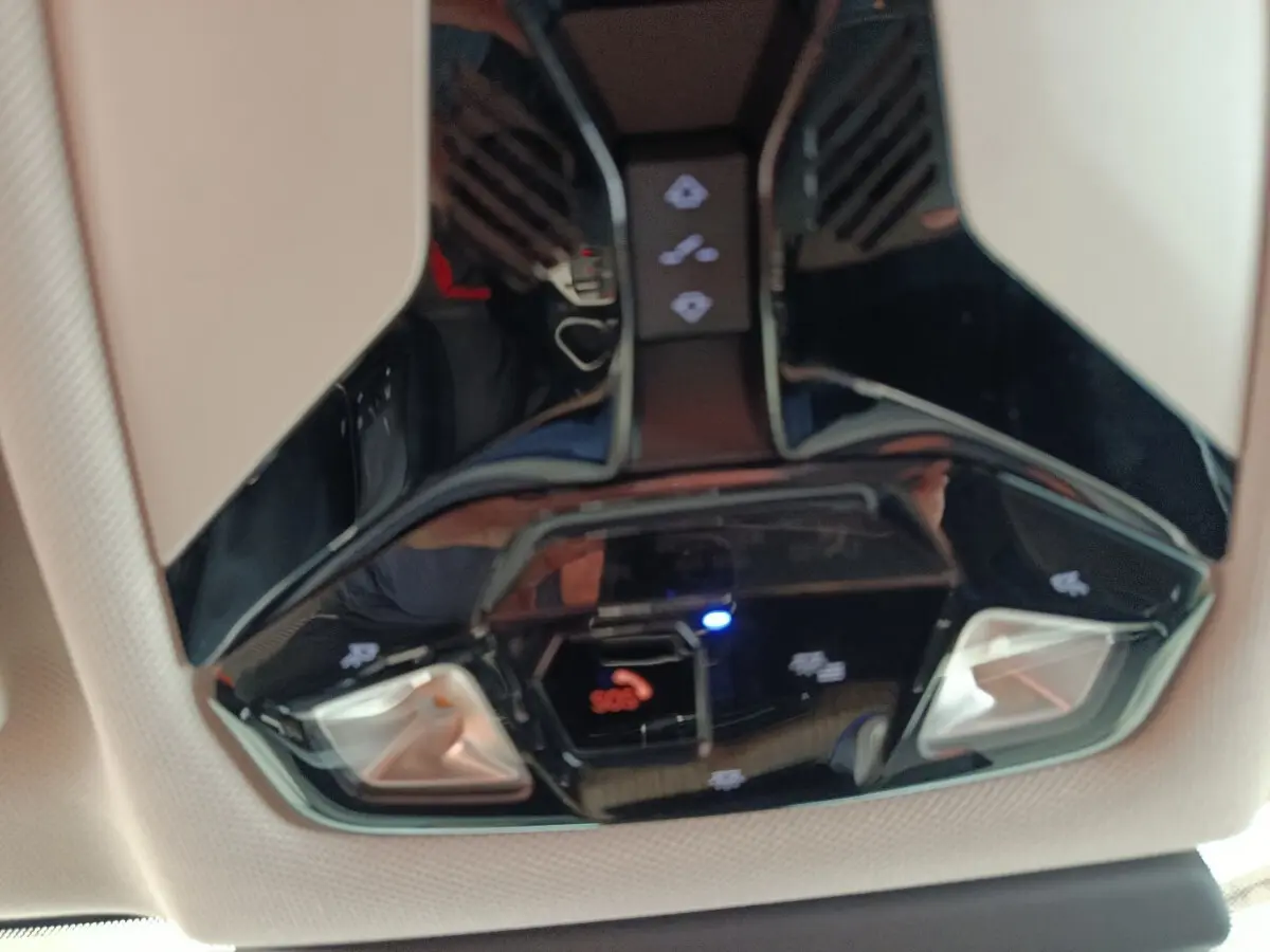 Gros plan sur le plafonnier noir brillant de la BMW X1 2023 avec commandes d’éclairage et bouton SOS.