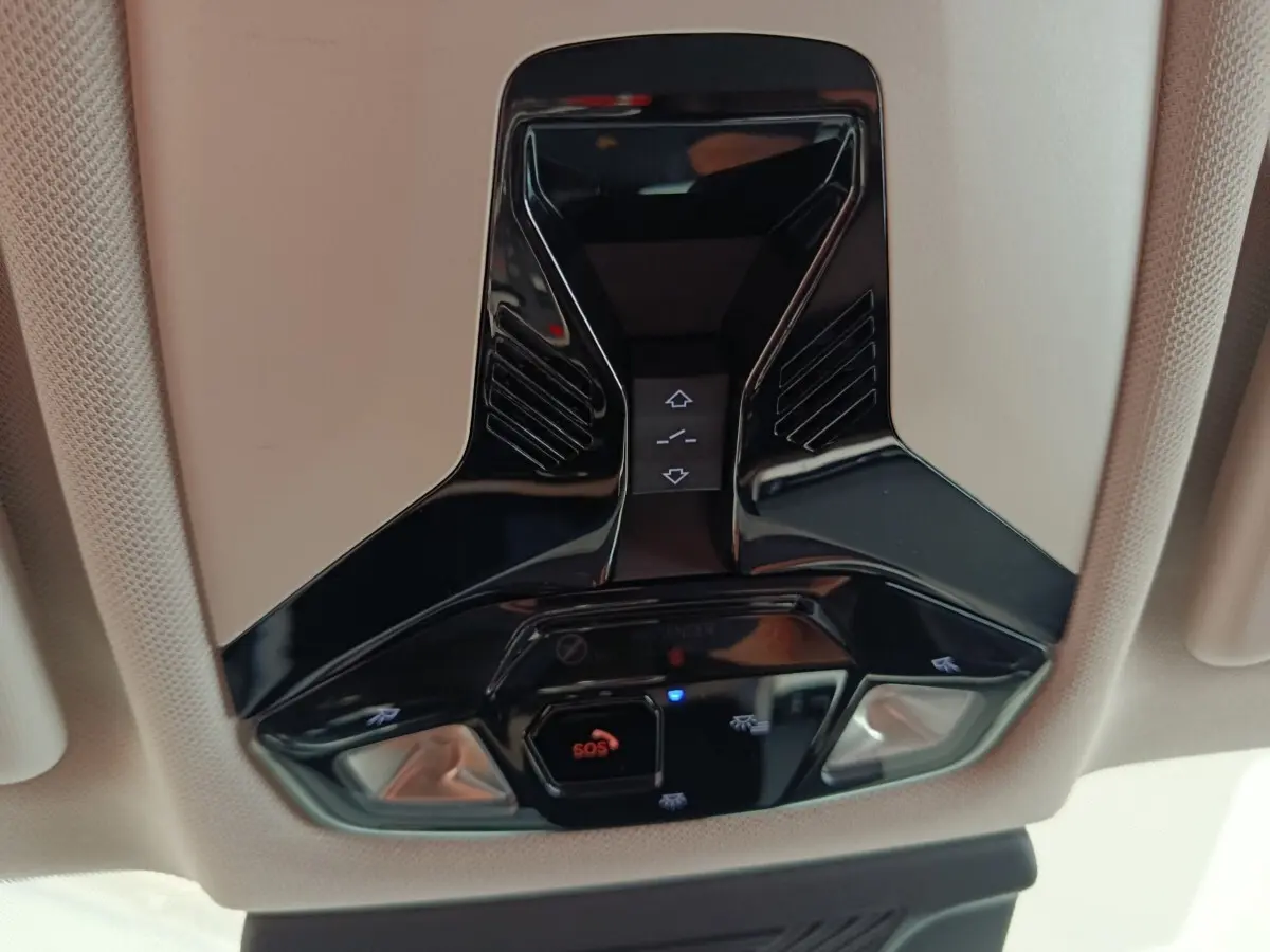 Vue en gros plan du plafonnier noir brillant avec commandes d'éclairage et bouton SOS dans un BMW X1 noir 2023.