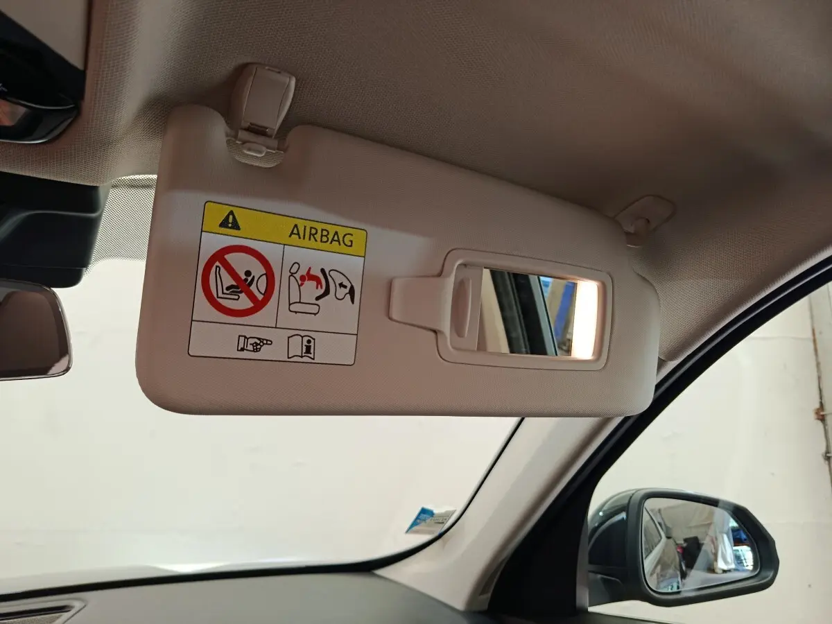 Vue intérieure côté conducteur du pare-soleil beige avec miroir et avertissement airbag sur BMW X1 noir 2023.