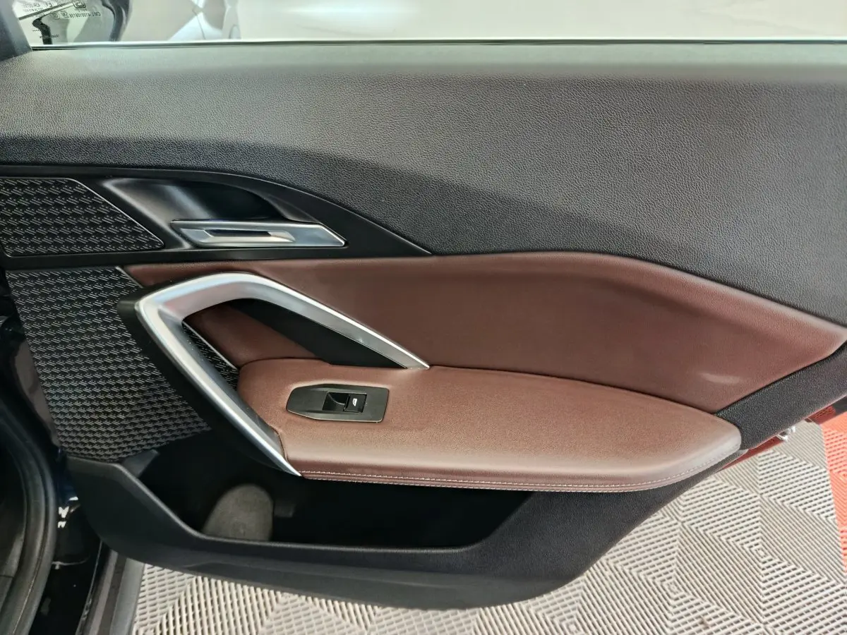 Gros plan sur la porte intérieure côté gauche de la BMW X1 2023, avec garniture marron et insert argenté.