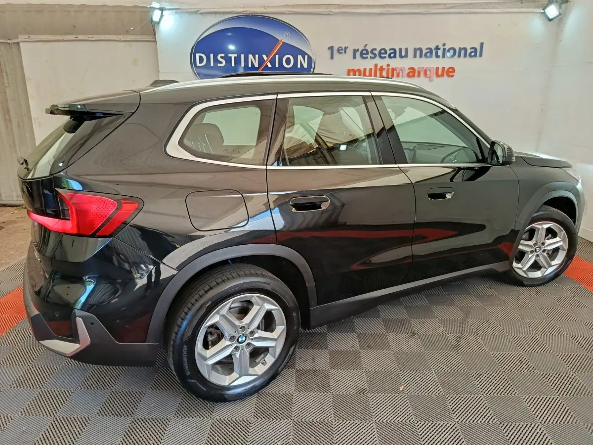 BMW X1 sDrive18i noir vue de profil côté droit, avec jantes alliage et feux arrière LED visibles.