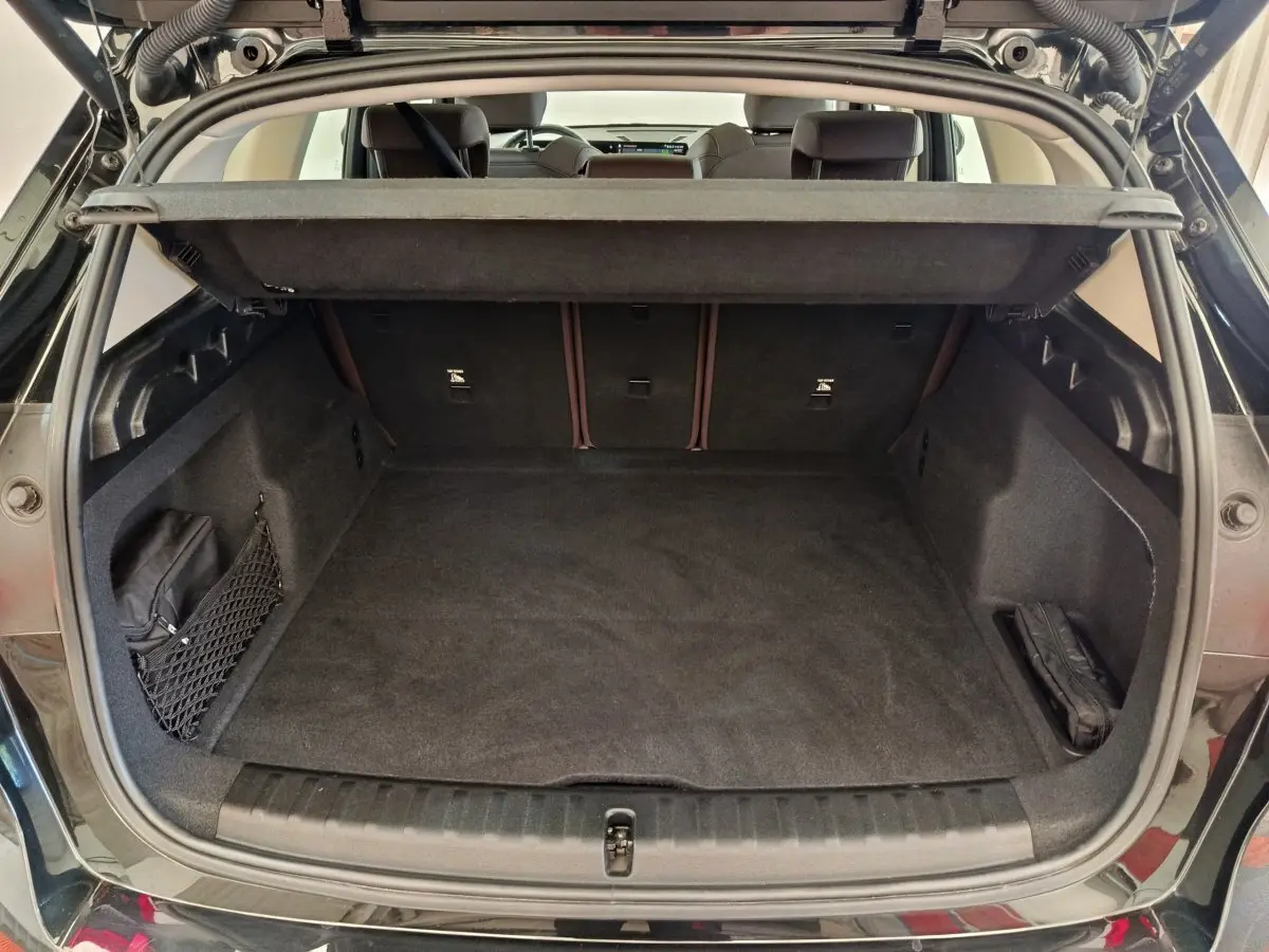 Coffre ouvert vu de l'arrière d'un BMW X1 noir 2023, espace de chargement propre et bien agencé.