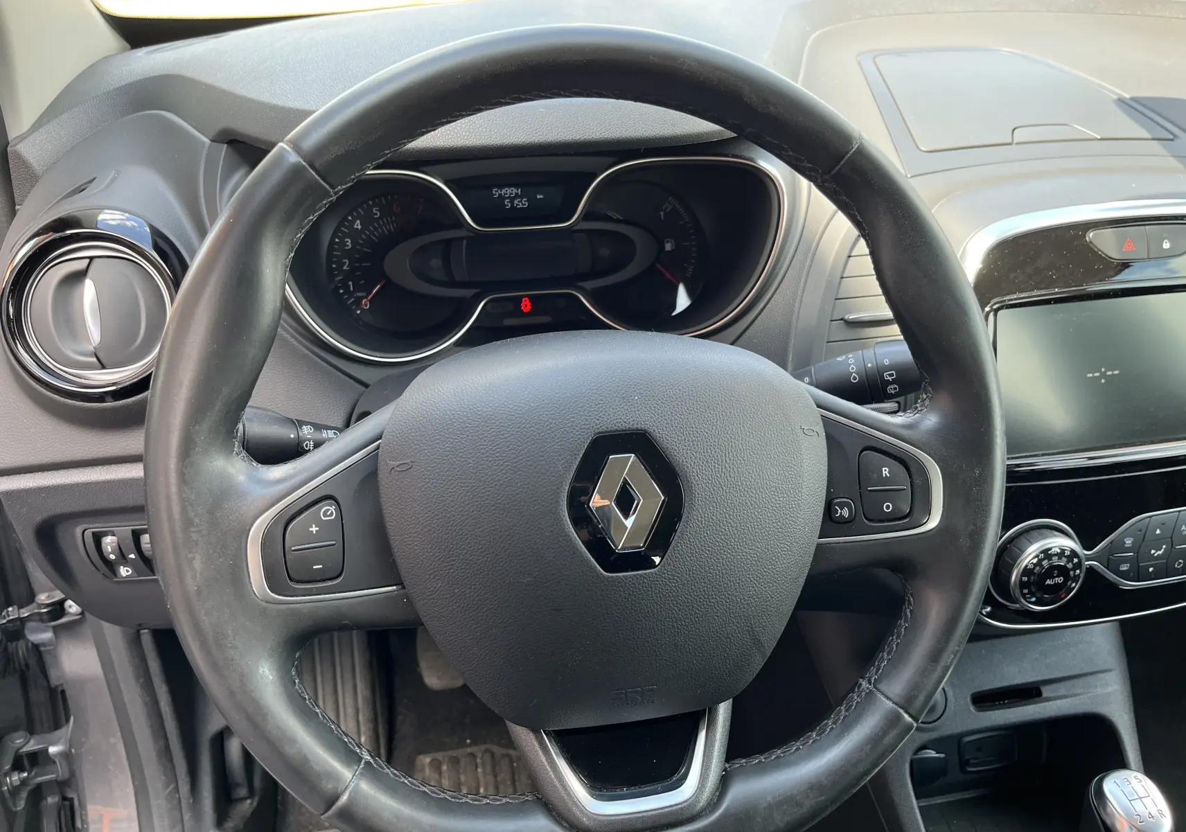 Intérieur du Renault Captur 2019 essence gris, vue sur le volant cuir, tableau de bord et console centrale avec écran tactile.
