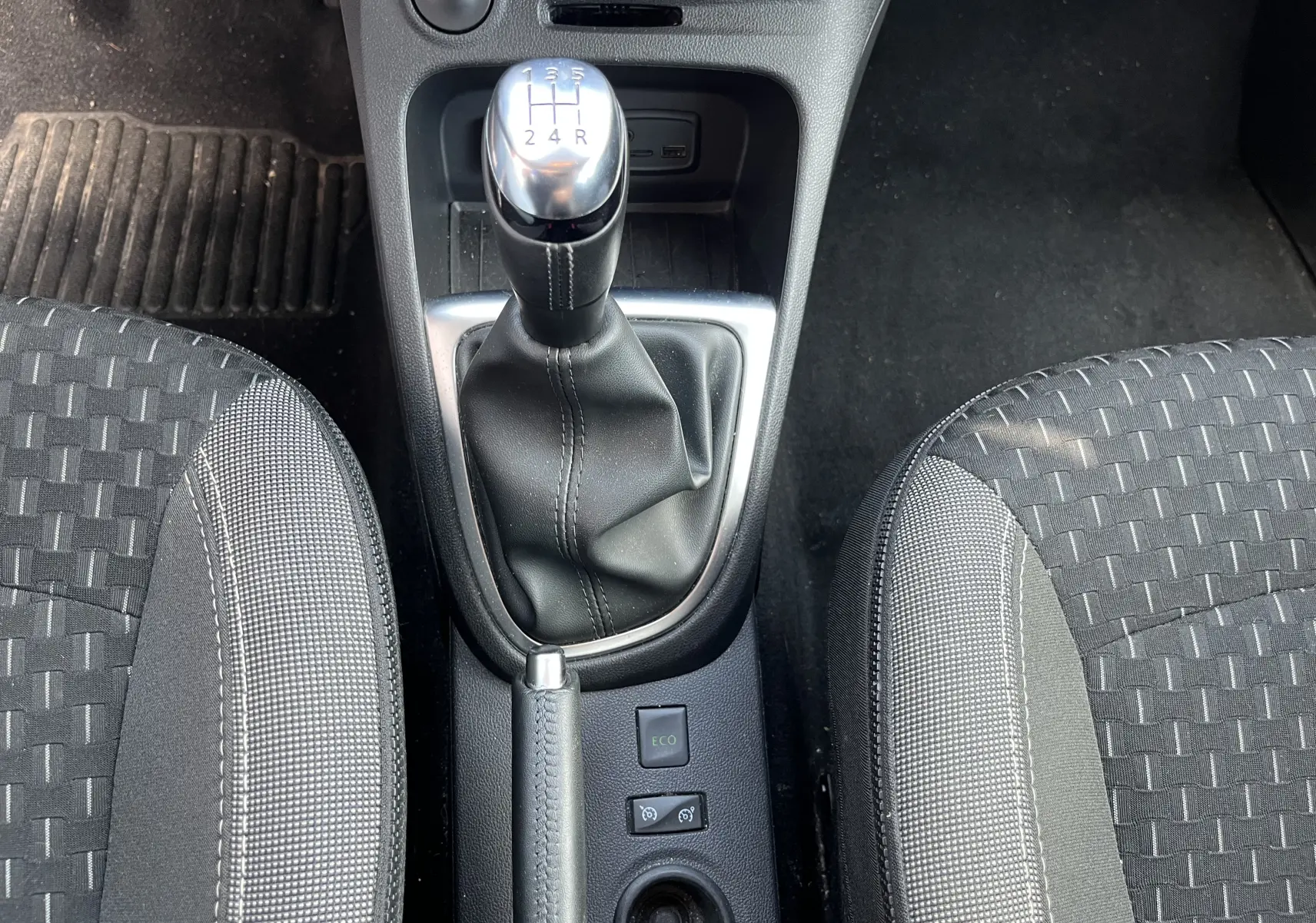 Le levier de vitesses manuel et le frein à main entre deux sièges tissu gris foncé à motifs dans un Renault Captur 2019.