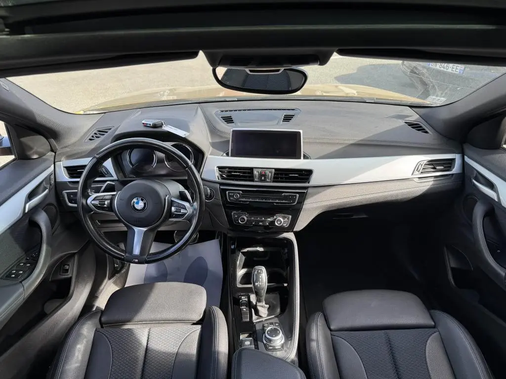 Vue intérieure avant du BMW X2 M Sport 2021, tableau de bord noir avec volant cuir M et écran central intégré.