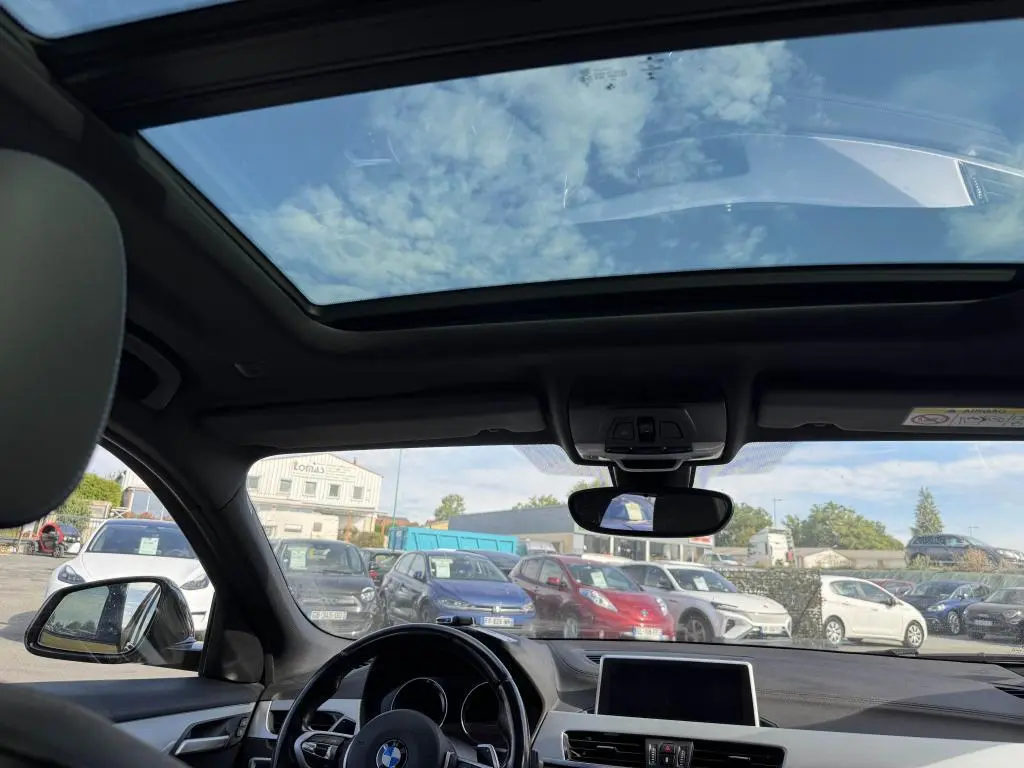 Vue intérieure du toit ouvrant panoramique en verre du BMW X2 sDrive 18d M Sport 2021 avec ciel bleu visible.