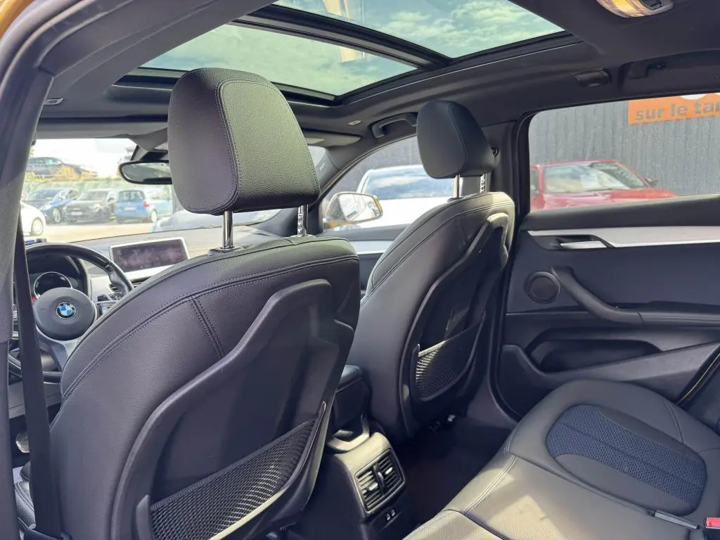 Vue intérieure arrière du BMW X2 M Sport 2021 avec toit ouvrant panoramique et sellerie noire en similicuir et tissu.