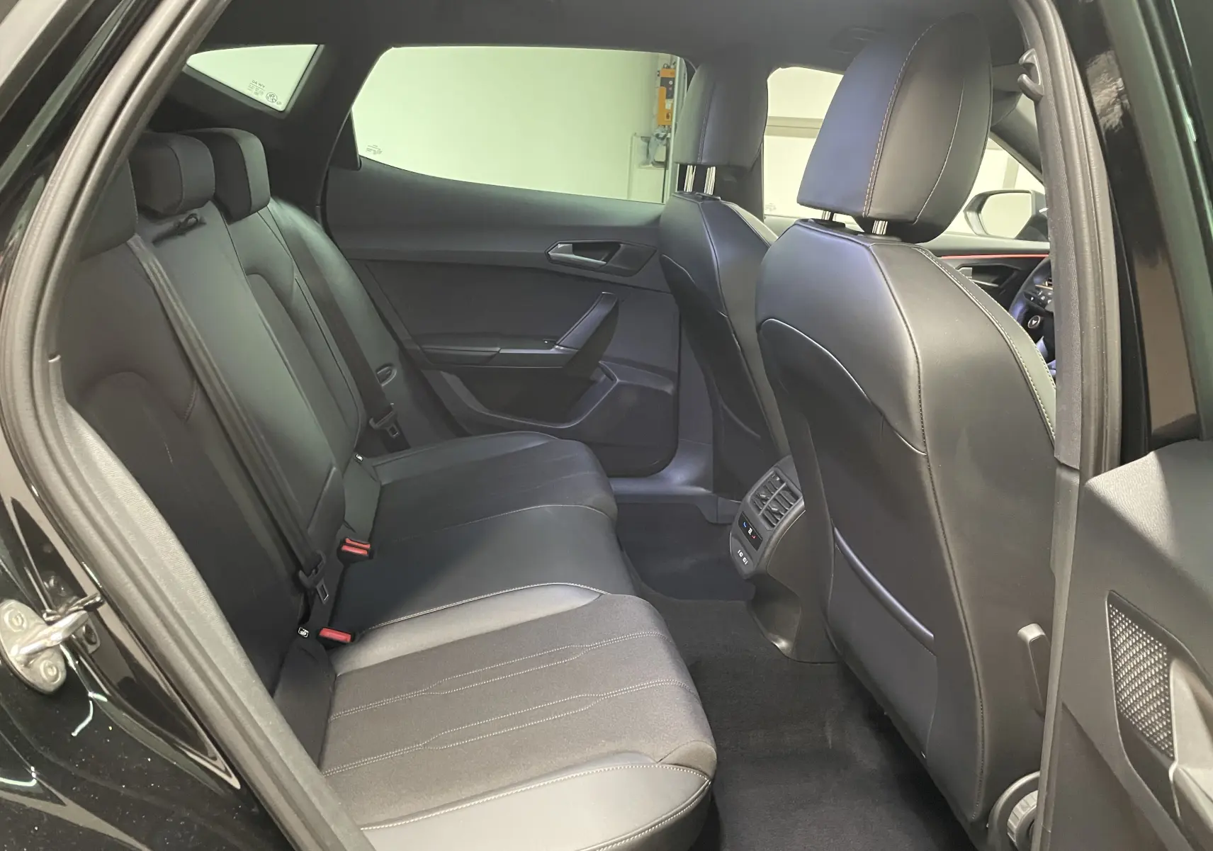 Vue intérieure arrière côté gauche du CUPRA Formentor noir Minuit, montrant les sièges arrière en cuir et les aérateurs centraux.