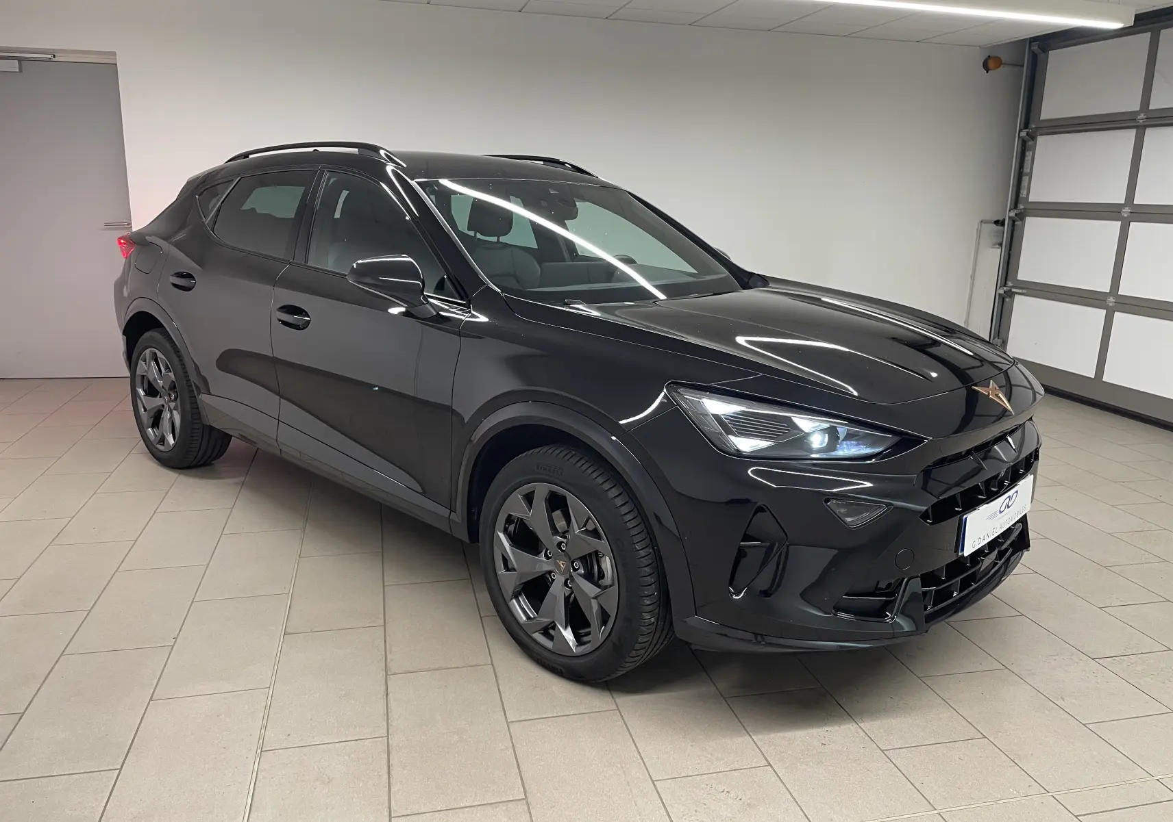 SUV CUPRA Formentor noir minuit vu en 3/4 avant droit dans un garage, avec phares allumés et jantes foncées.