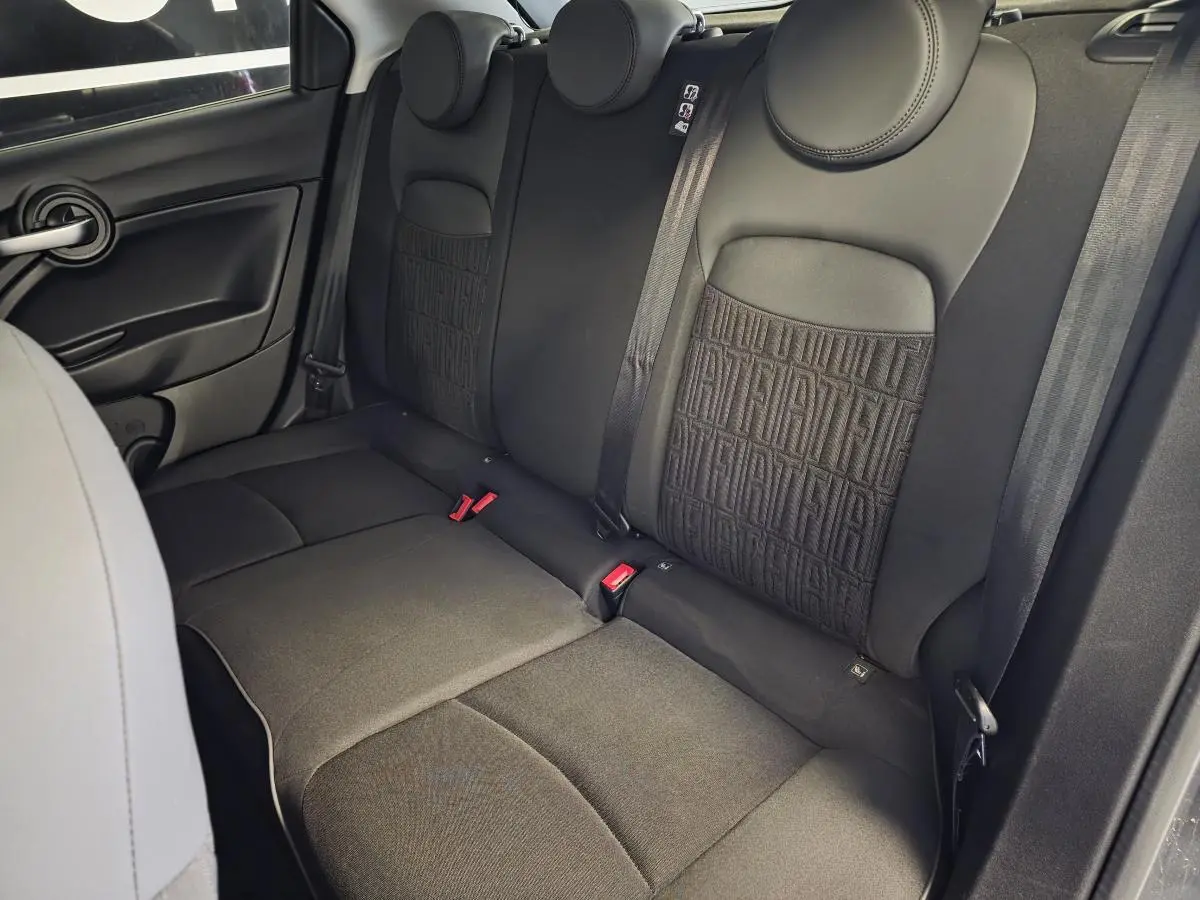 Vue latérale des sièges arrière noirs avec monogramme FIAT du Fiat 500X 2024, intérieur tissu urbain.