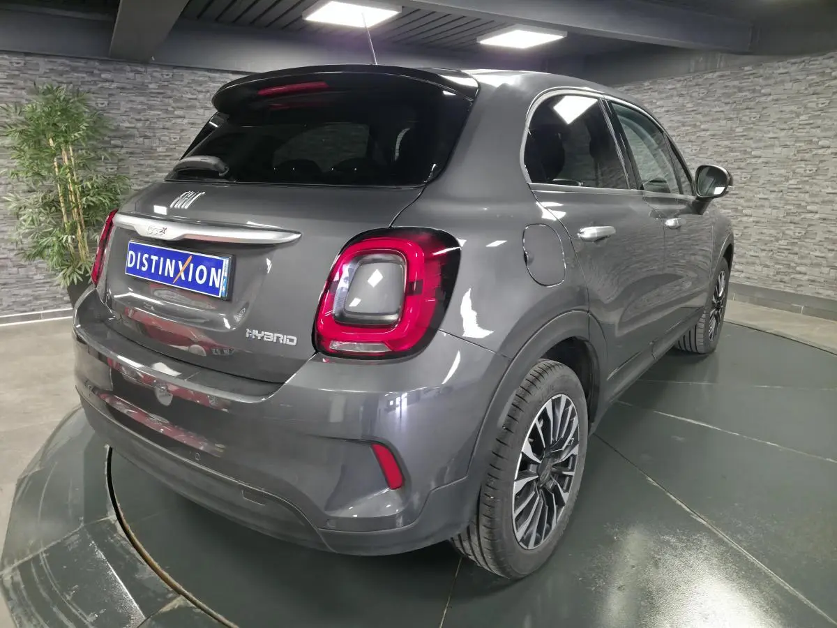 Vue 3/4 arrière droite du Fiat 500X gris avec feux arrière LED et jantes alliage 17 pouces dans un showroom.