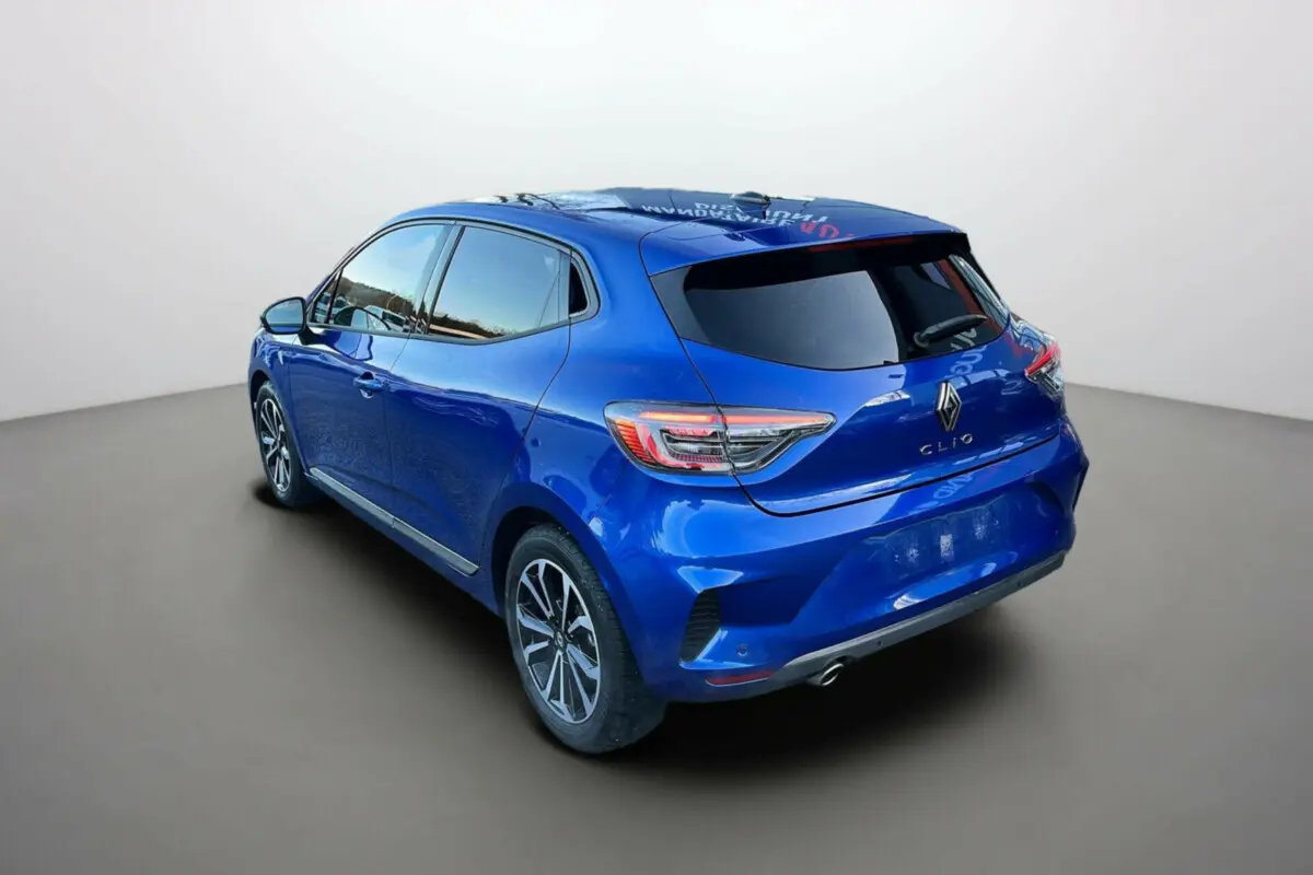 Renault Clio V TCE 90 Techno Plus bleu iron vue 3/4 arrière droit avec vitres surteintées et jantes alu noires.