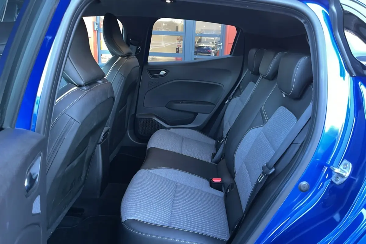 Vue intérieure des sièges arrière gris et noir de la Renault Clio V TCE 90 Techno Plus bleu iron avec porte ouverte côté droit.