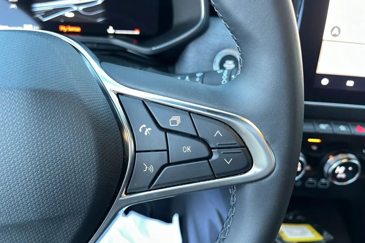 Gros plan sur le volant cuir multifonctions de la Renault Clio V TCE 90 Techno Plus avec commandes intégrées.