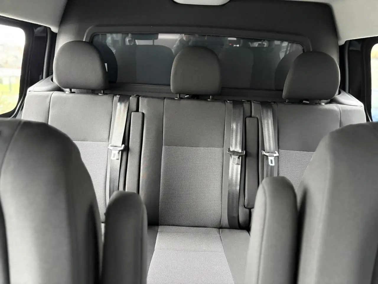 Vue intérieure sur la banquette arrière grise du Citroën Jumpy XL 2025 avec appuie-têtes et ceintures de sécurité.