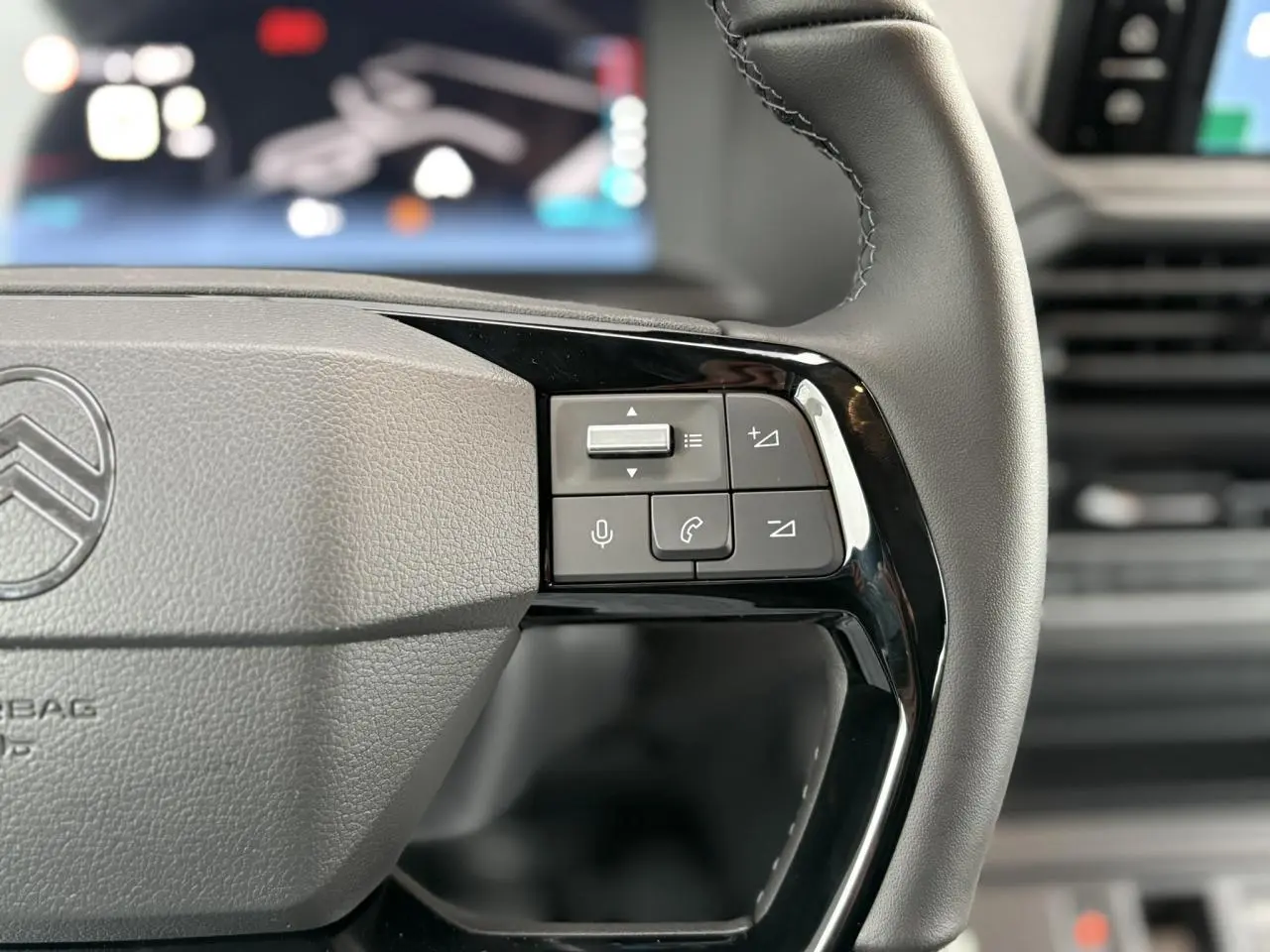 Gros plan sur le volant cuir gris du Citroën Jumpy XL 2025 avec commandes audio et téléphone intégrées.
