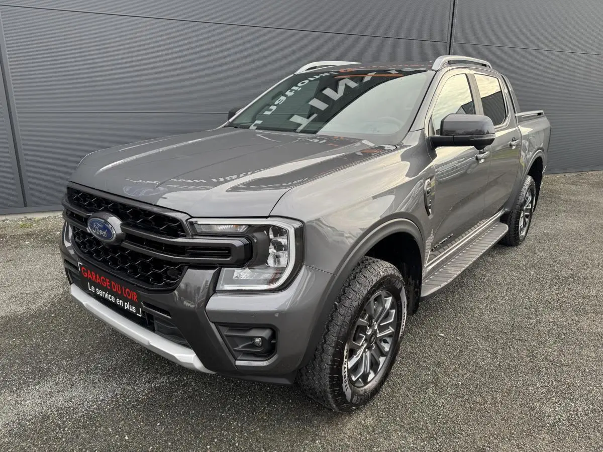 Ford Ranger 2025 gris, vue 3/4 avant droit, avec calandre noire et marchepieds latéraux métalliques.