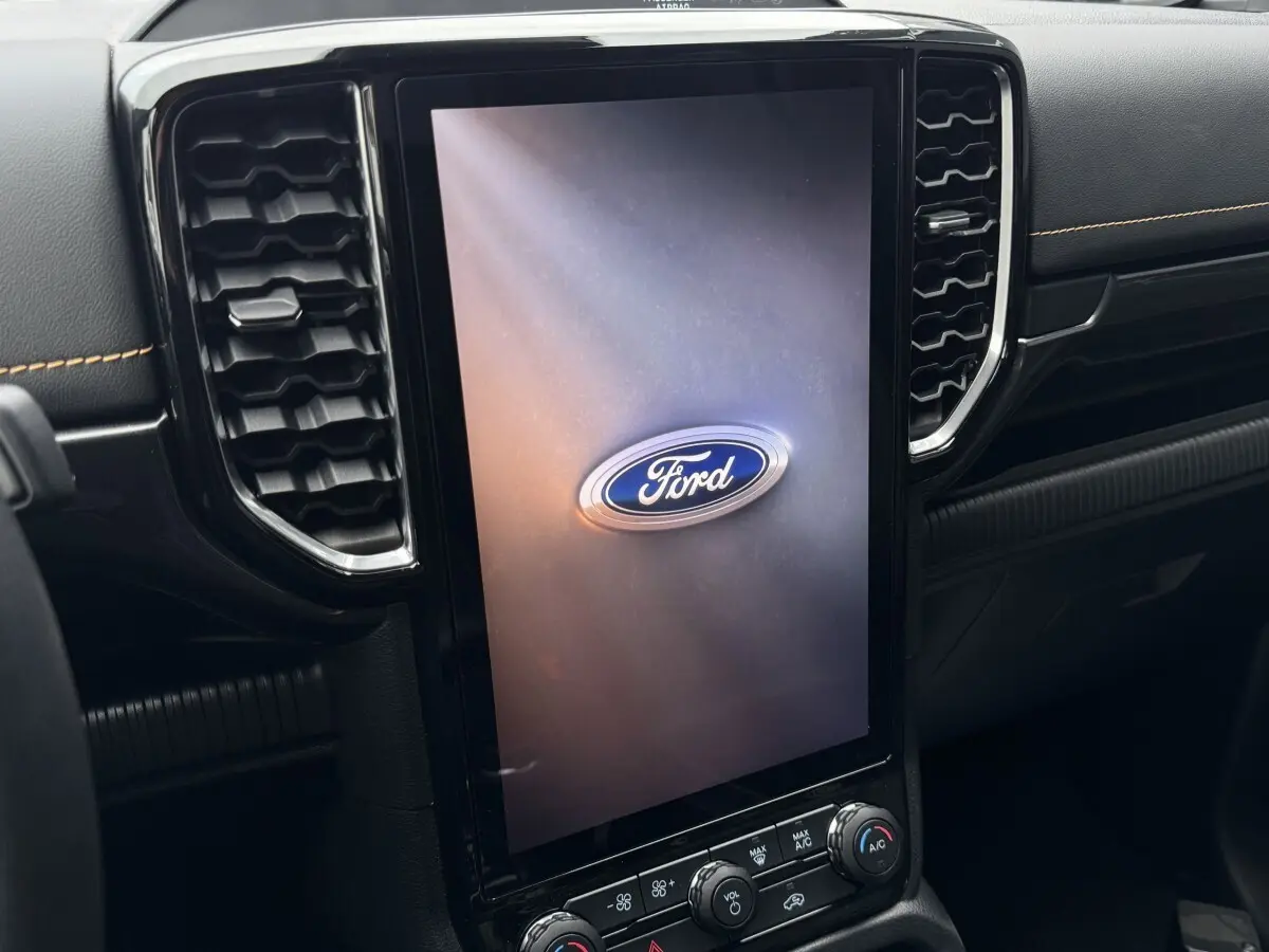 Vue rapprochée de l'écran tactile vertical central noir avec logo Ford, entouré de la console intérieure noire du Ford Ranger.