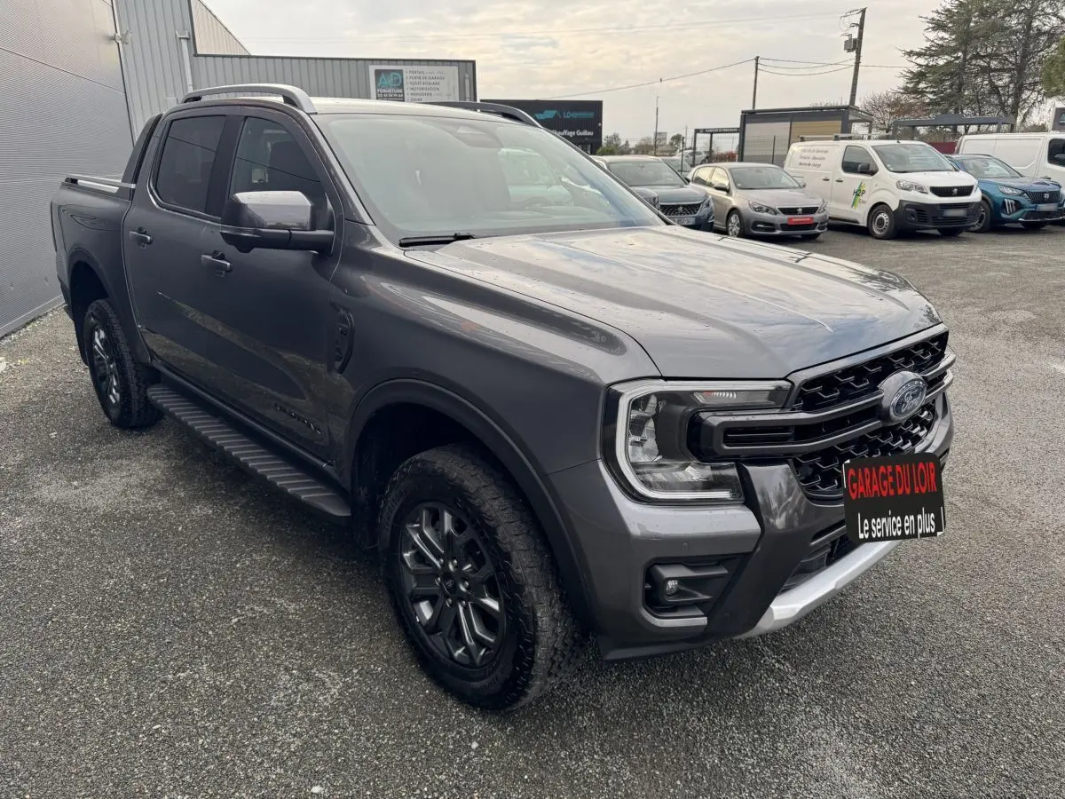 Ford Ranger Wildtrak gris foncé en 3/4 avant droit, avec calandre noire et jantes alliage sombres.