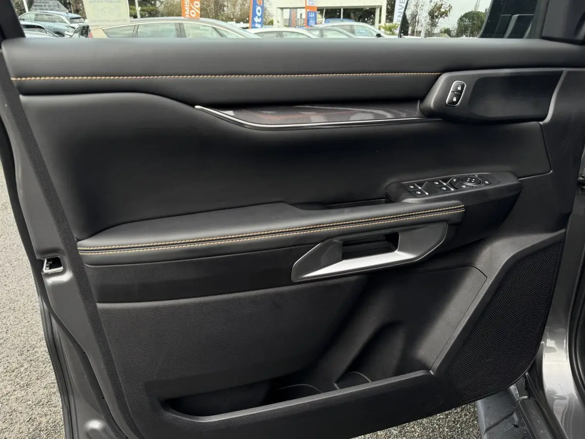 Vue intérieure côté gauche de la porte avant d’un Ford Ranger 2025 avec garniture noire et surpiqûres jaunes.