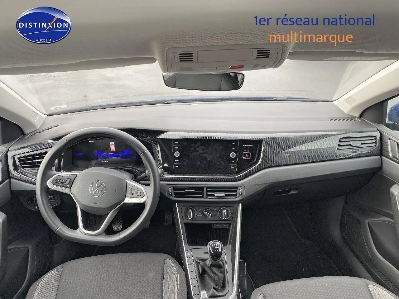 Vue intérieure avant du tableau de bord et volant cuir multifonction de la Volkswagen Polo bleu récif, avec levier de vitesse manuel.