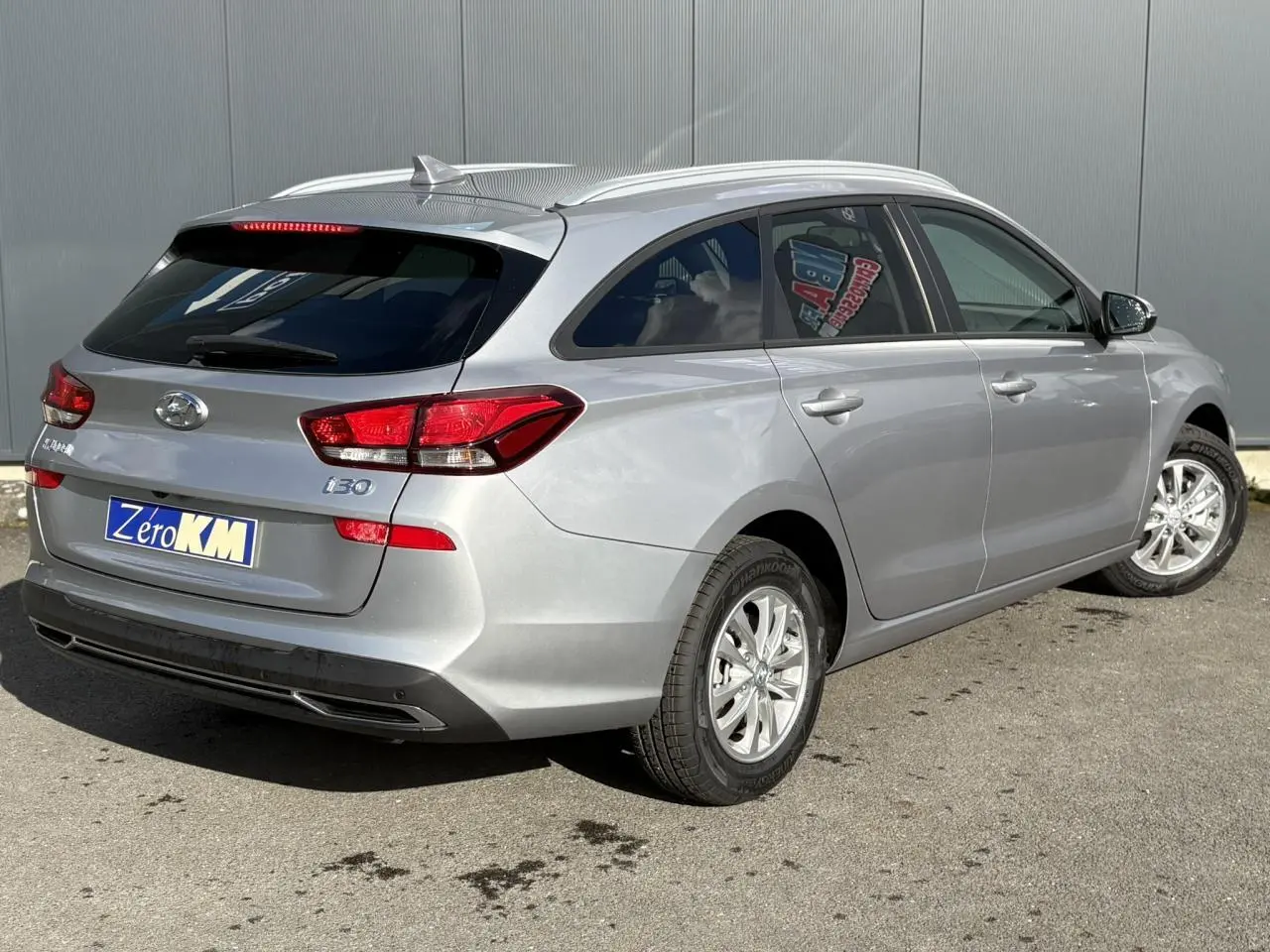 Vue 3/4 arrière droite d'une Hyundai i30 SW T-GDI 120 Modern gris argent avec jantes alliage et vitres arrière surteintées.