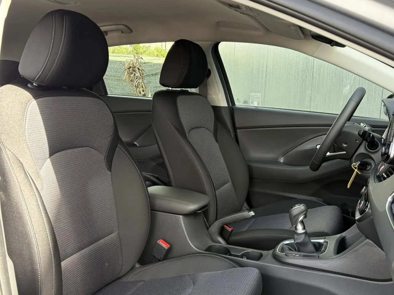 Vue intérieure côté droit montrant les sièges avant noirs et gris et la console centrale d'une Hyundai i30 SW T-GDI 120 Modern 2025.