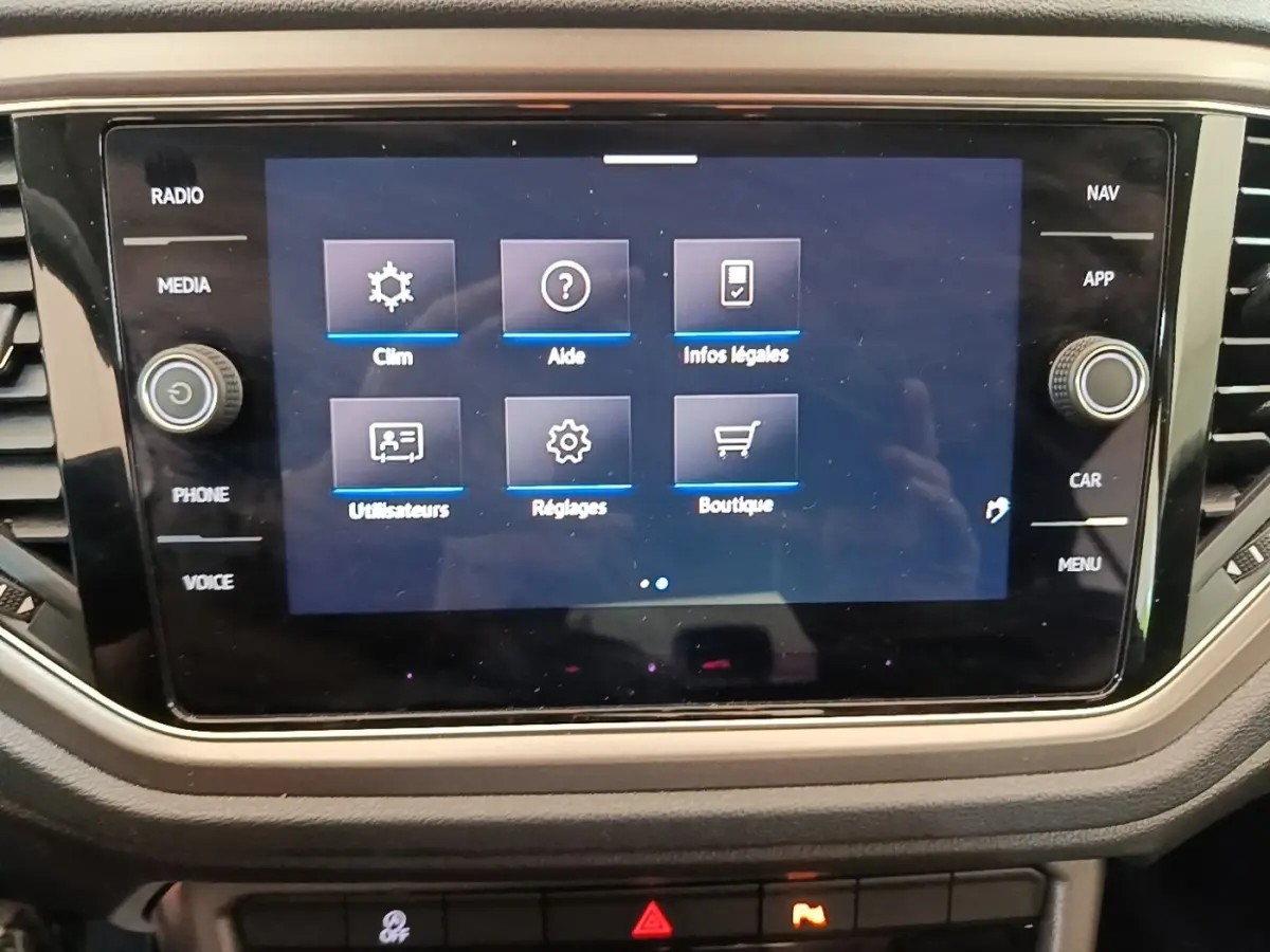 Écran tactile central du tableau de bord du Volkswagen T-Roc 1.5 TSI bleu, affichant le menu des réglages.