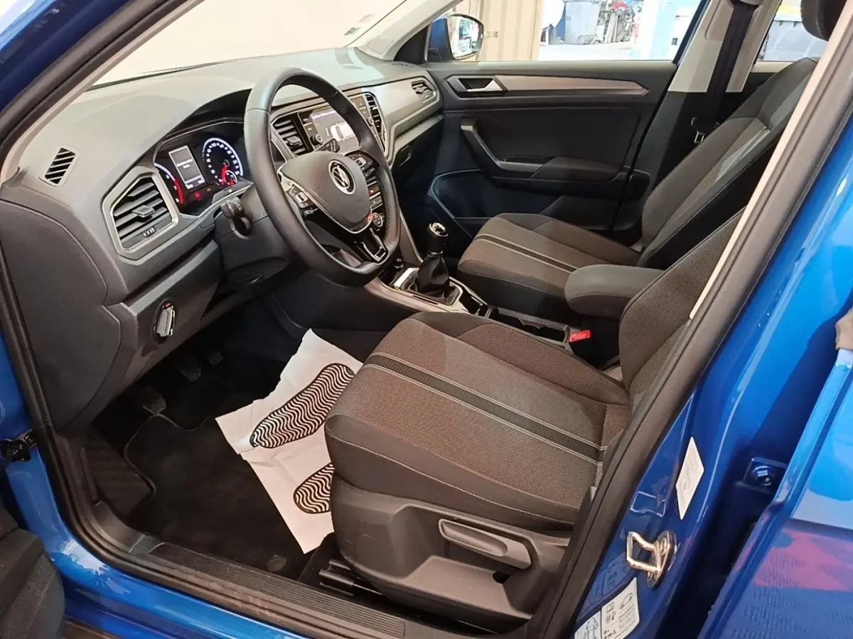 Vue intérieure côté conducteur du Volkswagen T-Roc bleu 2020, montrant tableau de bord et sièges tissu noirs.