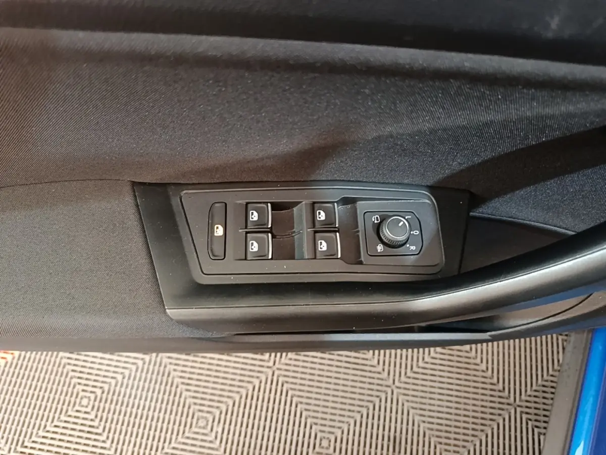 Vue rapprochée des commandes des vitres et rétroviseurs sur la porte côté conducteur du Volkswagen T-Roc bleu.