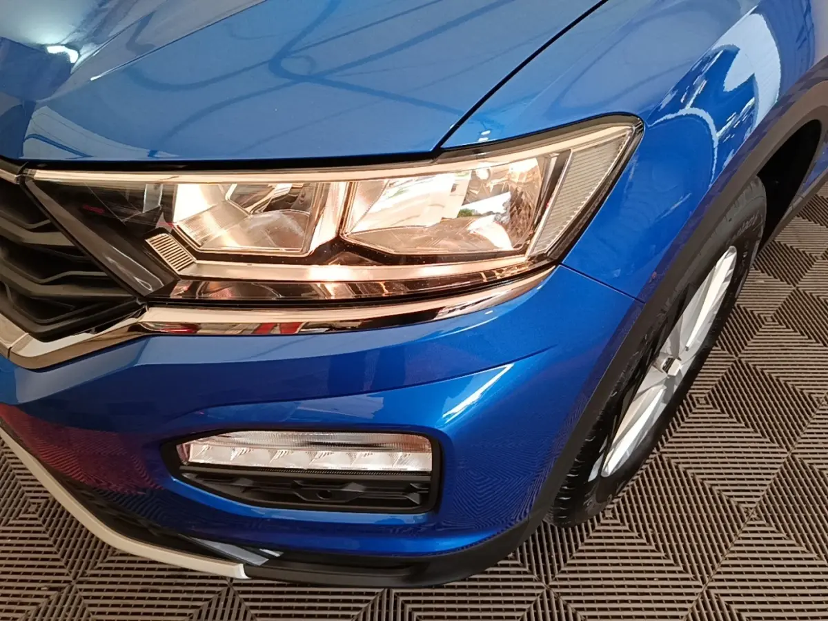 Gros plan sur l'avant droit bleu du Volkswagen T-Roc 1.5 TSI 150 EVO UNITED, mettant en valeur les phares et la calandre.