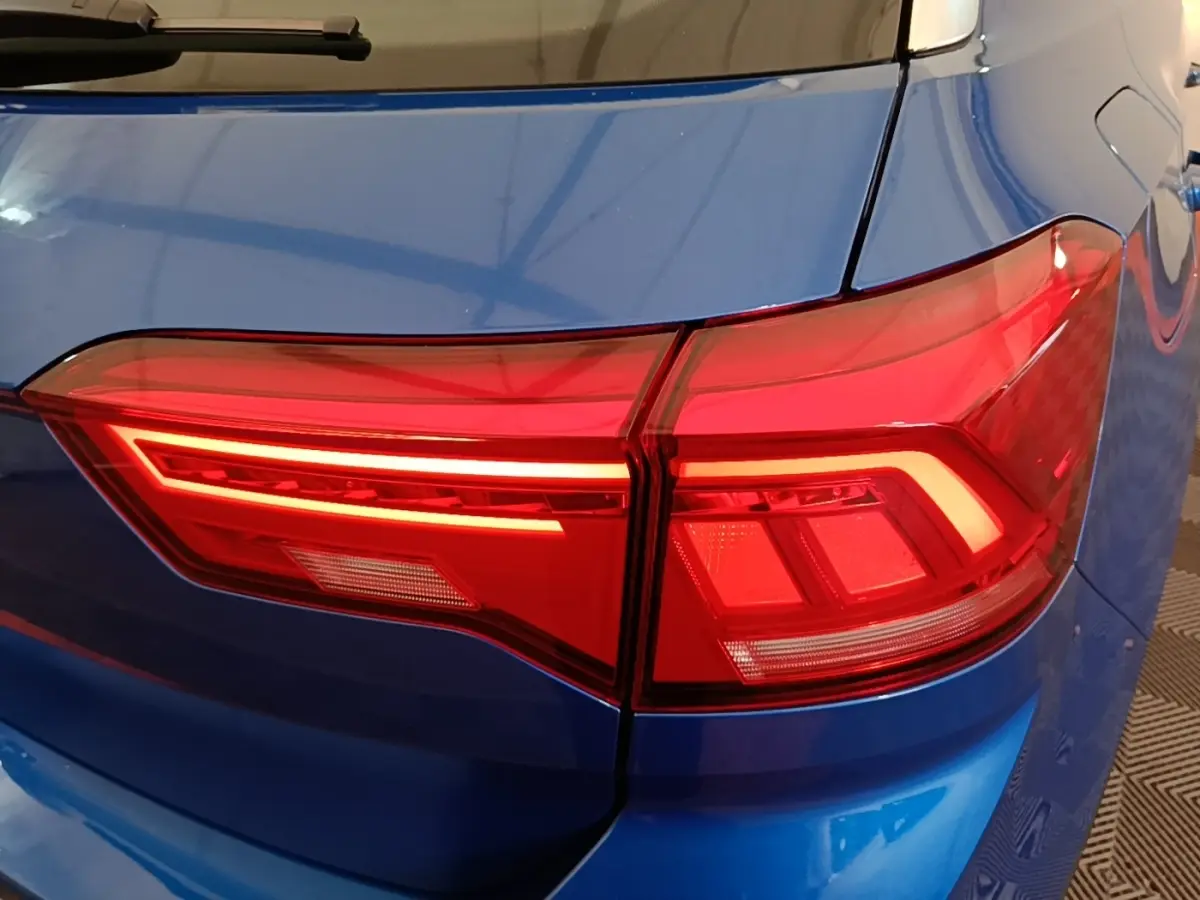 Gros plan sur le feu arrière droit rouge d’un Volkswagen T-Roc bleu 2020, soulignant la carrosserie brillante.