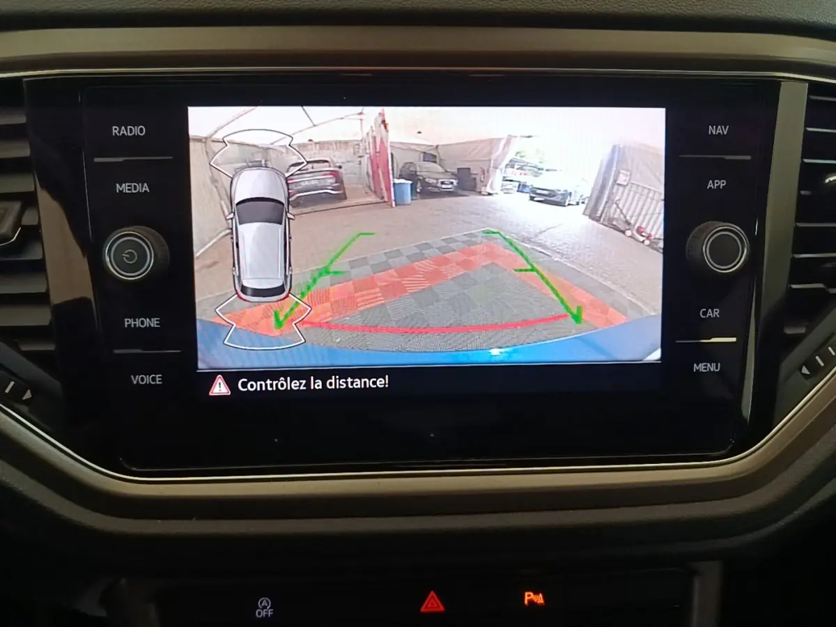 Écran tactile intérieur montrant la caméra de recul du Volkswagen T-Roc bleu, vue arrière avec guidage de trajectoire.