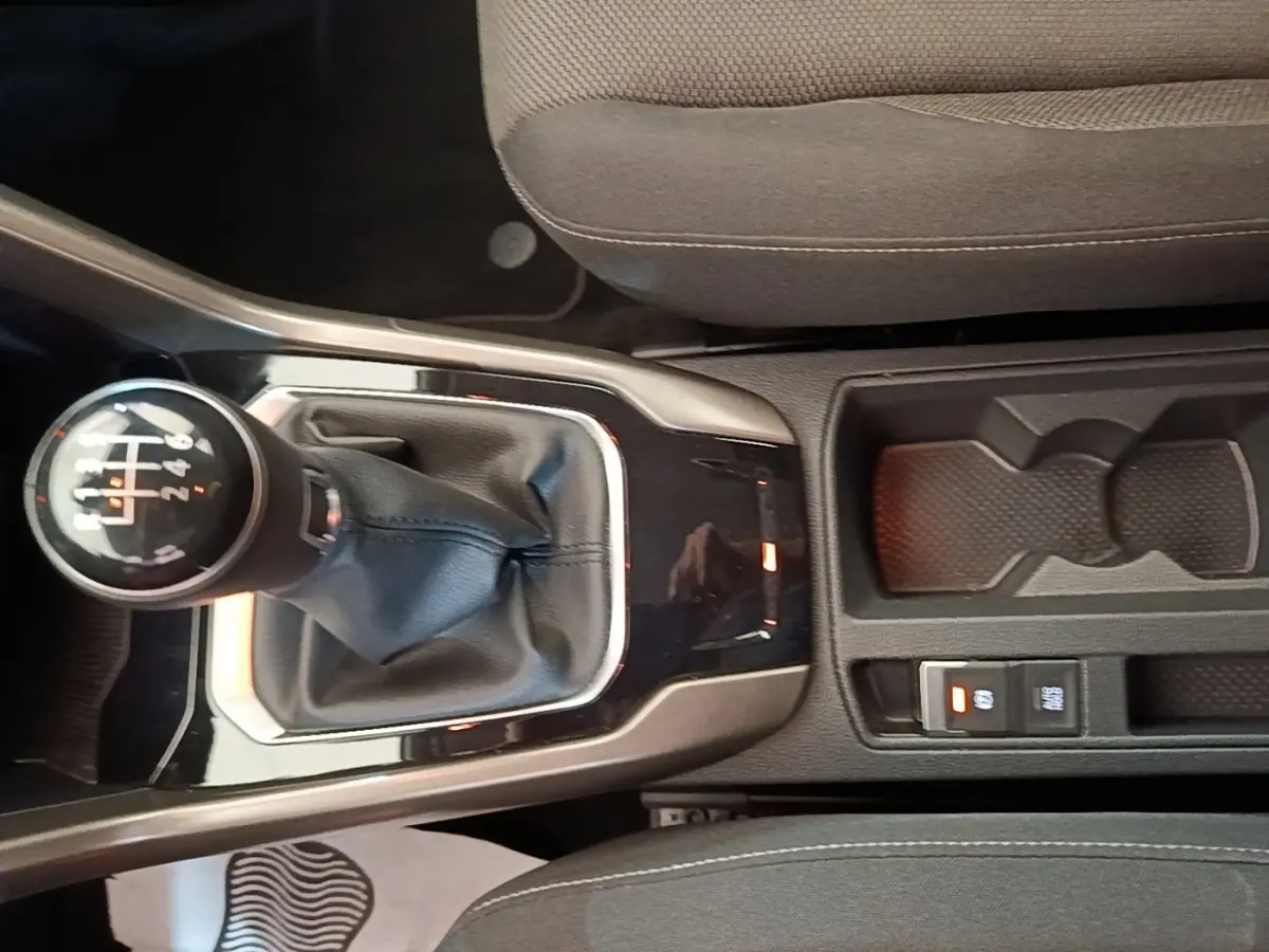 Gros plan sur la console centrale du Volkswagen T-Roc bleu 2020, avec levier de vitesse manuel et rangement porte-gobelets.