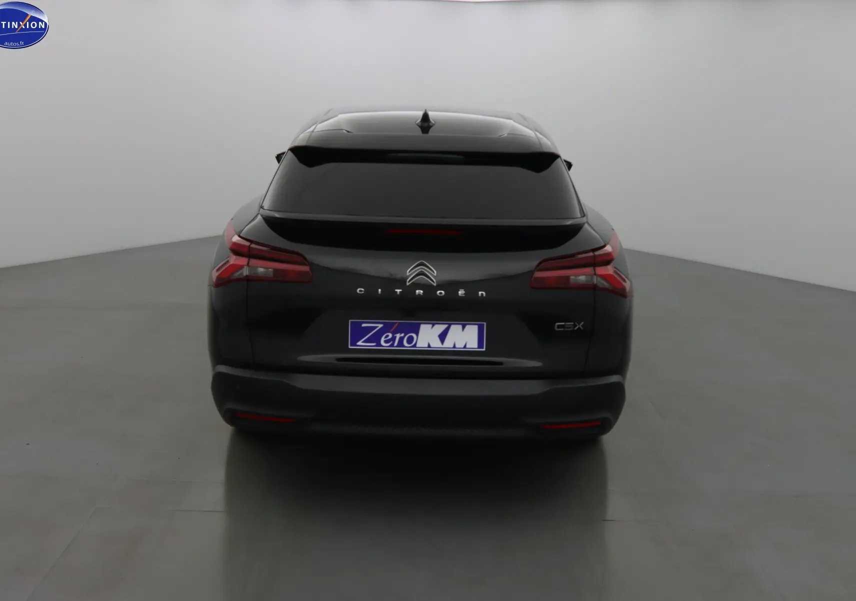 Vue arrière d'une Citroën C5 X noire métal 2023 avec feux arrière étirés et vitre arrière teintée.