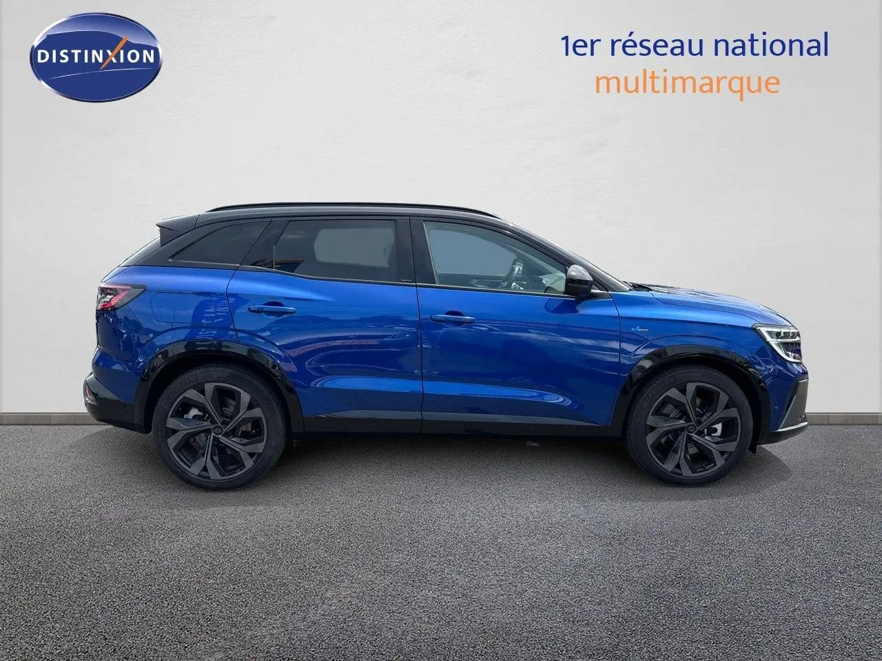 Profil droit d'un Renault Austral E-Tech hybride bleu Iron Metal avec toit noir, soulignant ses jantes noires et lignes modernes.