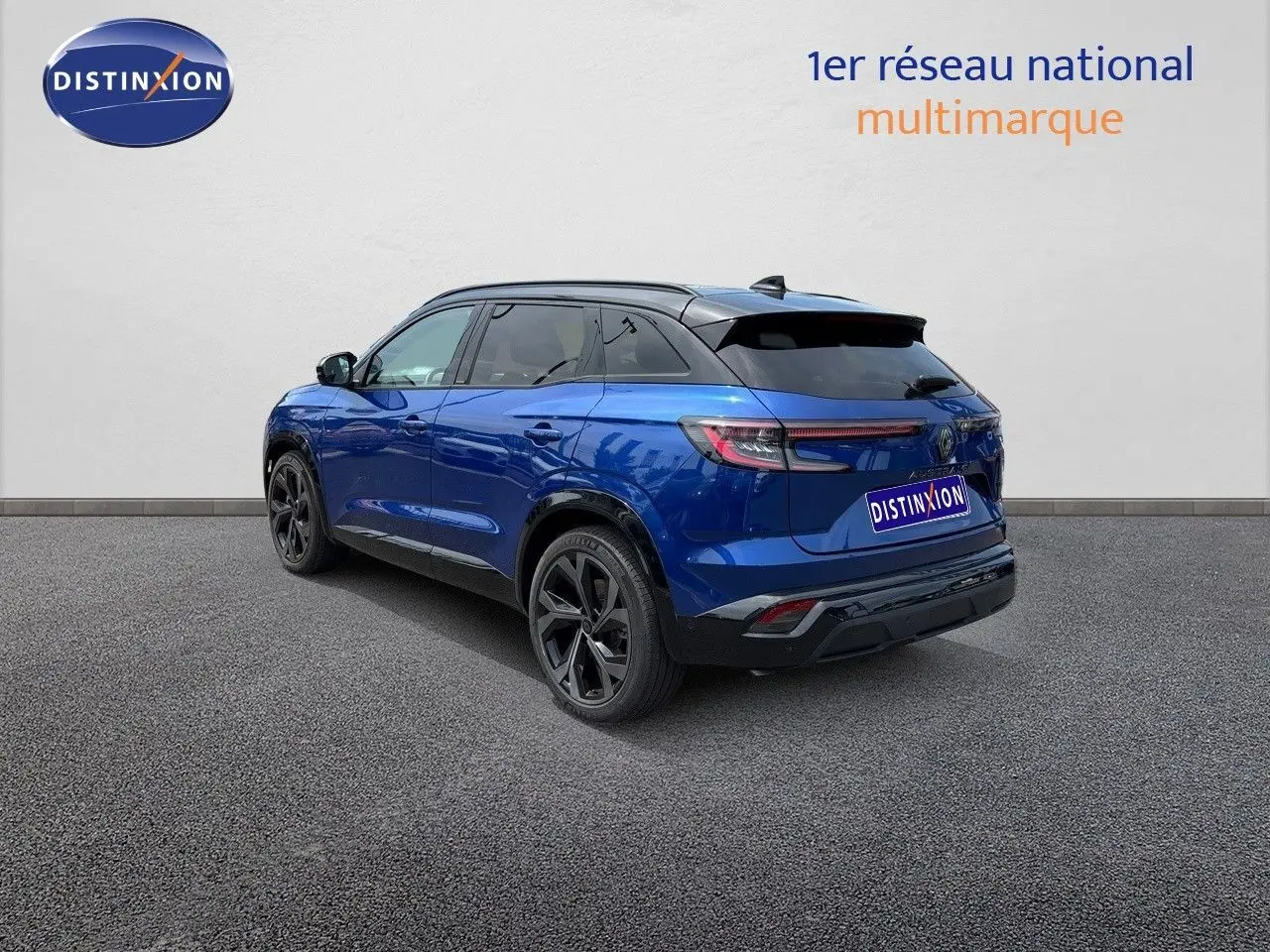 Vue 3/4 arrière d'un Renault Austral bleu Iron Metal avec toit noir et jantes noires sur fond neutre.