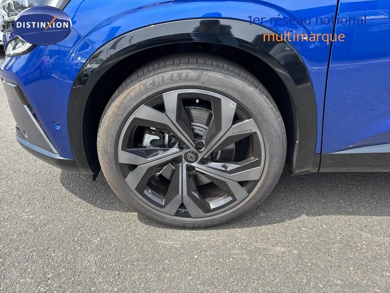 Gros plan sur la roue avant gauche du Renault Austral bleu Iron Metal avec jante noire Alpine et pneus Michelin.