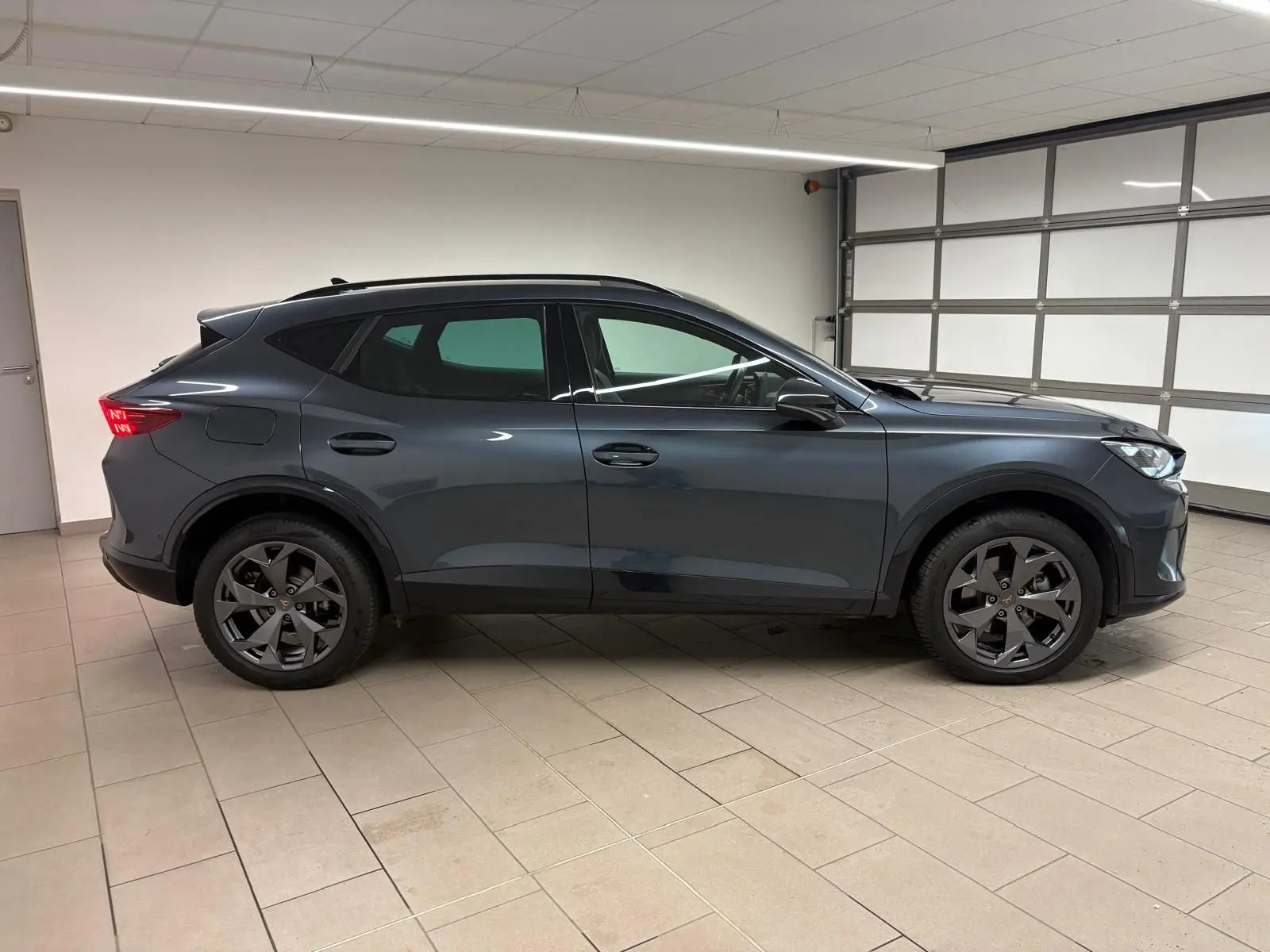 Profil côté gauche du CUPRA Formentor 2025 gris magnétique, avec jantes noires et attelage escamotable visible.