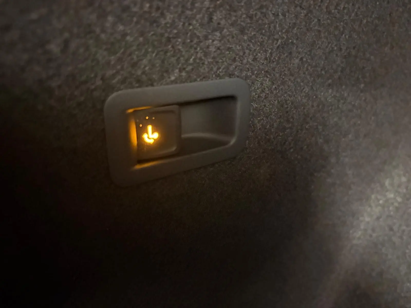Gros plan sur l'interrupteur lumineux de rabattement des sièges arrière dans le coffre du CUPRA Formentor gris magnétique.