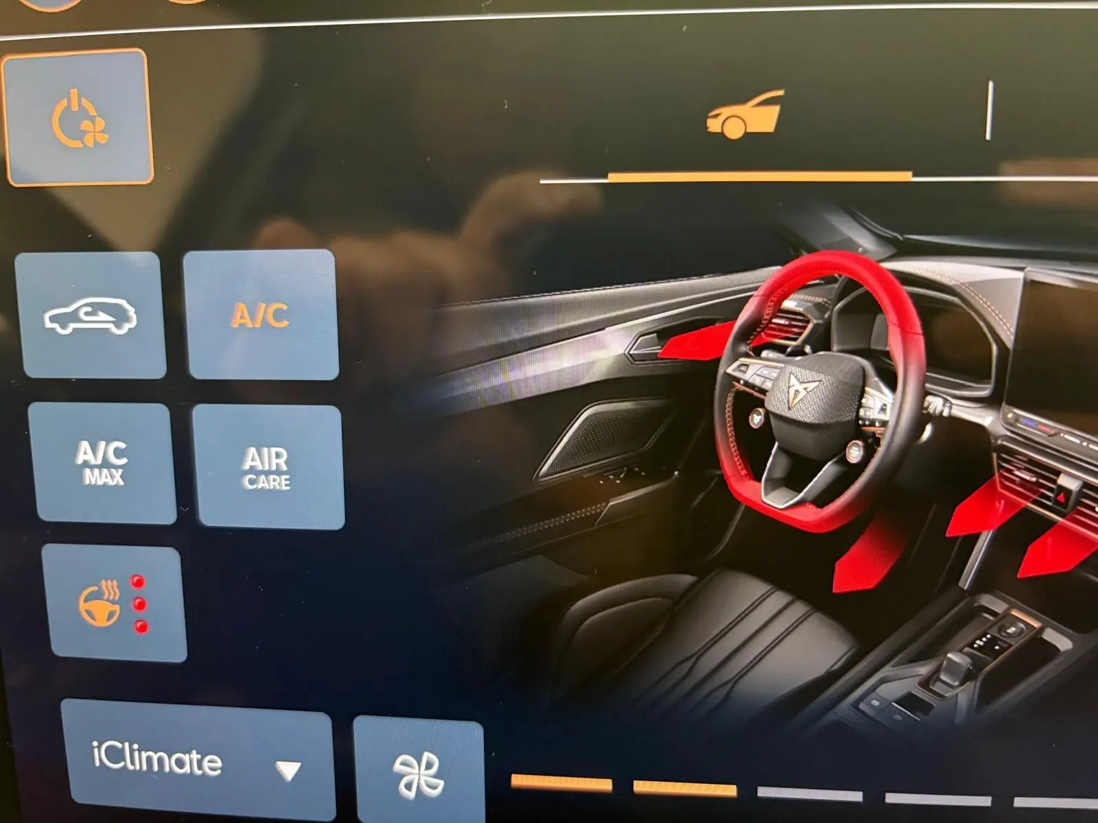 Affichage tactile montrant l'intérieur avant droit du CUPRA Formentor 2025 avec volant et commandes en surbrillance rouge.