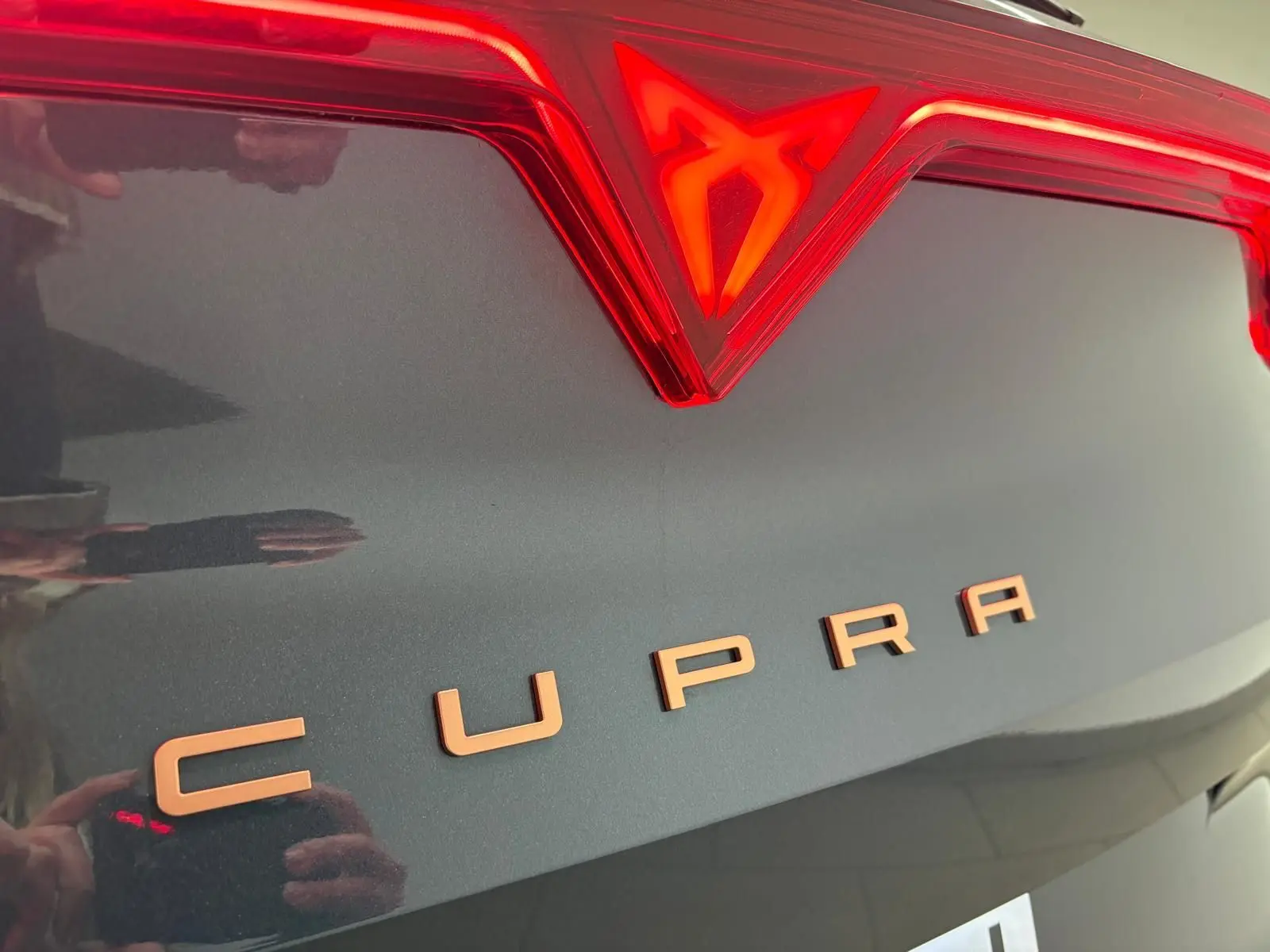 Gros plan sur le logo et le nom CUPRA en cuivre sur la malle arrière gris magnétique du Formentor 2025.